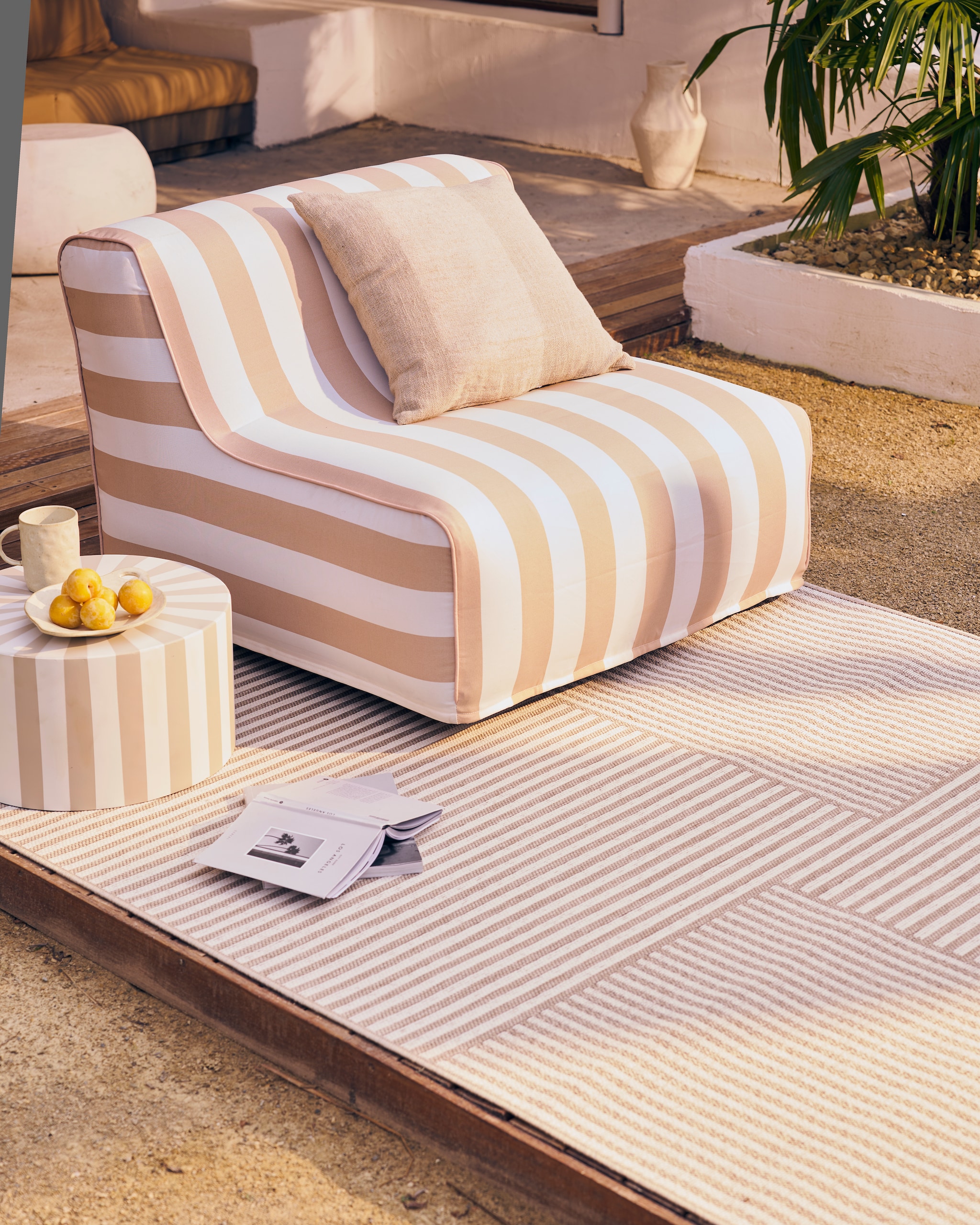 Opblaasbare fauteuil Sit on Air in zand-wit van waterproof outdoor polyester, 90x87x70 cm (lxbxh) € 119,-, ook verkrijgbaar in zwart-wit gestreept. Opblaasbare poef Sit on Air in zand-wit van waterproof outdoor polyester, 72x72x35 cm (lxbxh) € 69,95, ook verkrijgbaar in zwart-wit gestreept. Polypropyleen buitenkleed Toes and Stripes 160x230 cm € 99,99. M.m.v. vtwonen.nl/shop (kussen en bijzettafel van vtwonen), hm.com (beker, schaal), zarahome.com (beige vaas, plaid). Overig privébezit. vtwonen 05-2024 Huiscollectie tuinmeubels | styling Cleo Scheulderman | fotografie Jeroen van der Spek