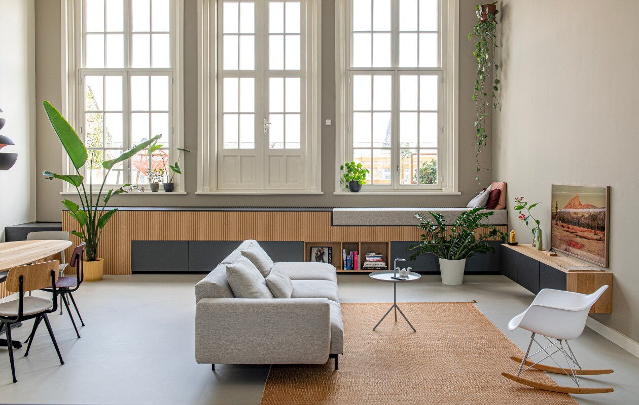 Eetkamerstoelen Revolt en bijzettafel DLM van Hay. Eettafel, kast onder de ramen en tv-meubel op maat gemaakt door Houtmerk. Bank en vloerkleed Muuto, schommelstoel Eames Rar van Vitra, plantenpotten van gerecycled plastic Elho, flesvaas Foekje Fleur, televisie The Frame van Samsung. Roze en rood kussen Muuto, kussen in de vorm van een berg op daybed gemaakt door Ingrids moeder. Overig onbekend. vtwonen special binnenkijken 11-2023 | productie De Binnenkijkers | styling Jeske Weel | fotografie Caroline Coehorst