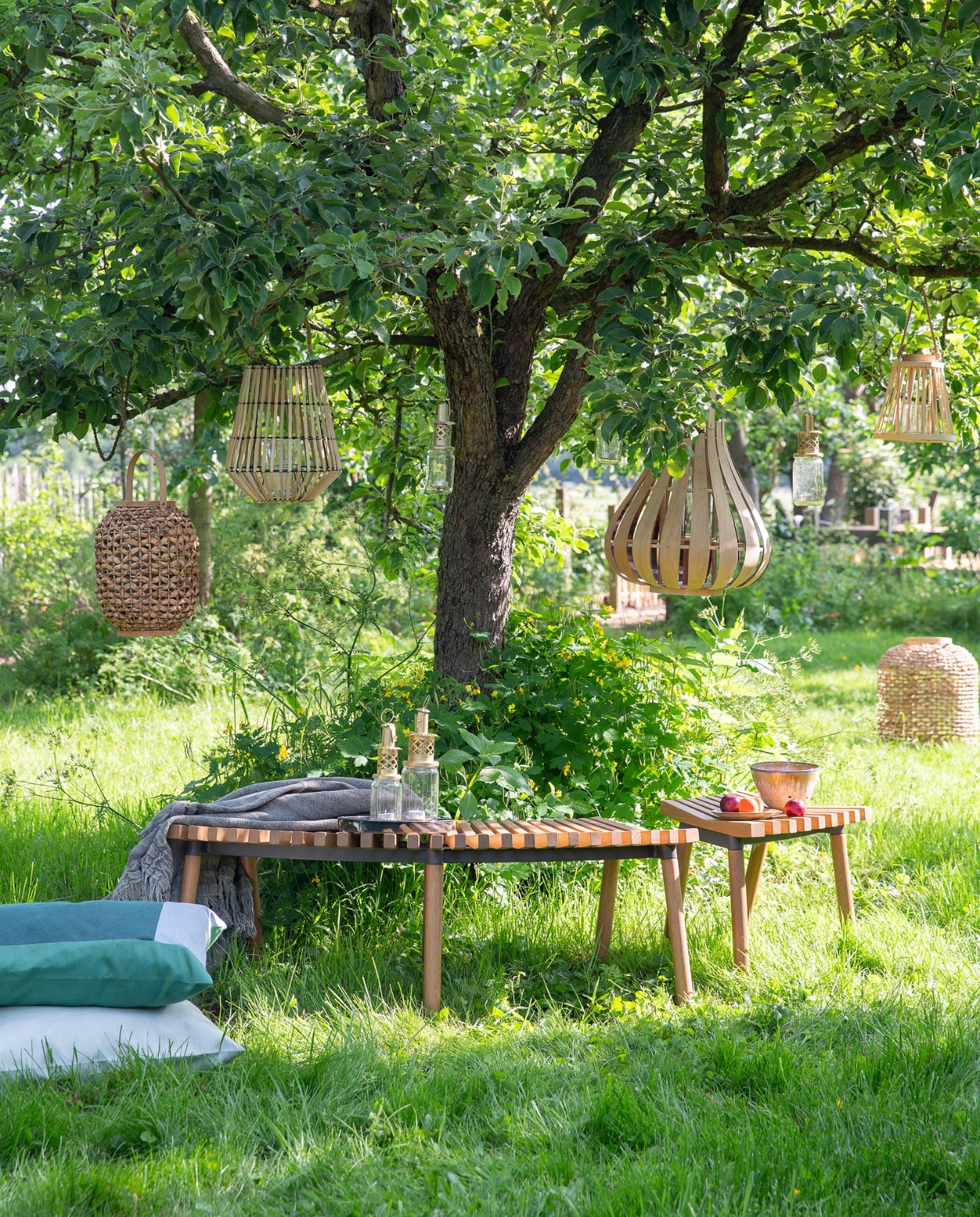 Bank Överallt, 124x49x44 cm (bxdxh) € 119,-, kruk Överallt € 49,95 (ikea.nl). Lantaarns van links naar rechts in de boom: XL van gevlochten gras en jute € 48,25 (deens.nl), van bamboe € 4,95 (action.com), jampot maat M € 19,95 (householdhardware.nl), van bamboe met glas erin van Pols Potten, 45x48 cm € 99,- (vtwonen.nl), jampot maat M € 19,95 (householdhardware.nl), taps toelopend van bamboe met glas erin € 7,95 (action.com). Lantaarn XXL van gevlochten gras en jute € 110,25 (deens.nl). Mintgroen duurzaam buitenkussen Solid, 60x60 cm € 110,-, mintgroen buitenkussen Bengali € 95,- (kus-sen.nl). Linnen plaid,130x170 cm € 125,- (aaimadewithlove.com). Lantaarns van gerecyclede jampotten vanaf € 15,95 (householdhardware.nl). Fruitschaal en schotel € 52,- (lilokeramiek.nl). vtwonen 08-2019 | styling Leonie Mooren | fotografie Anouk de Kleermaeker