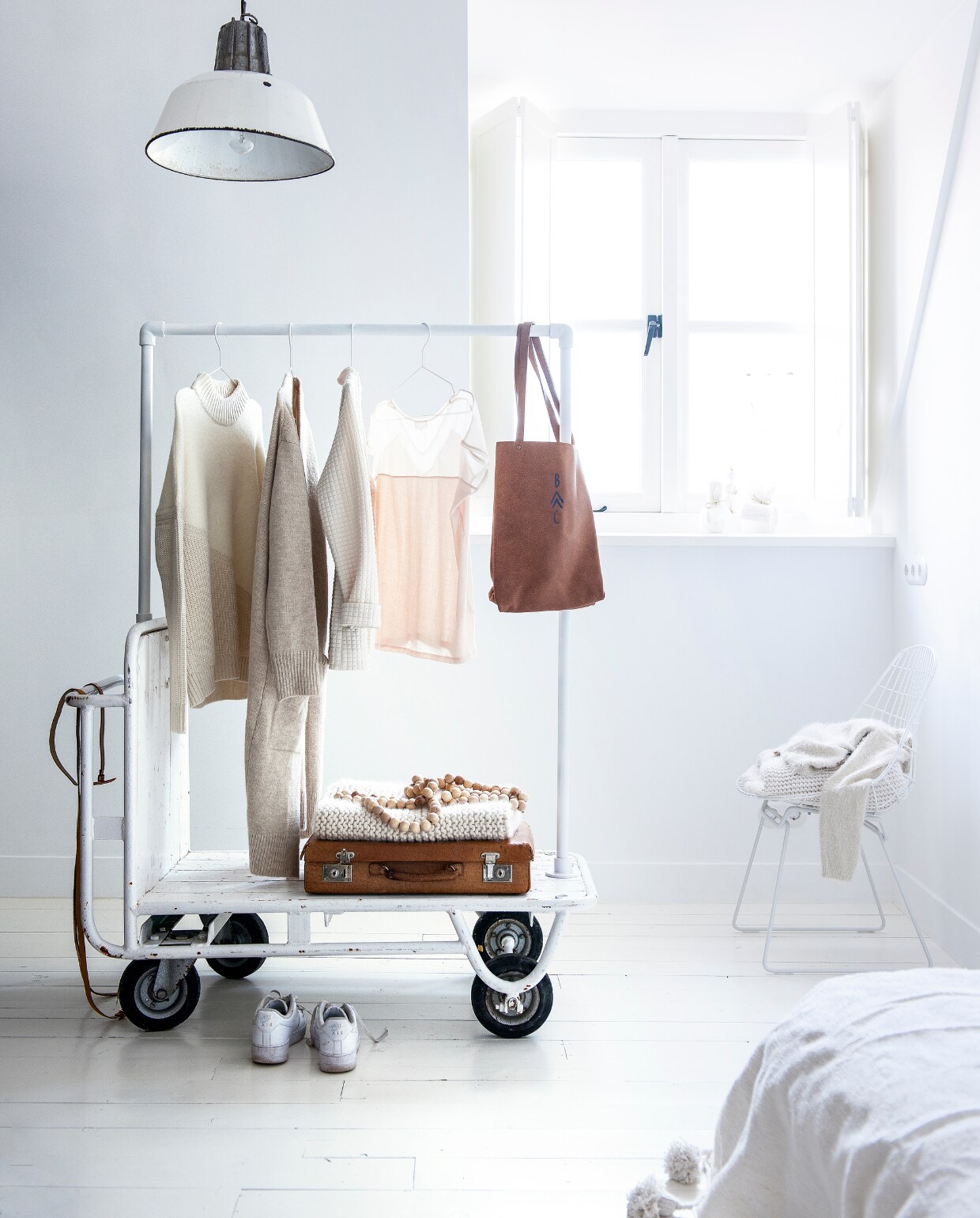 Hanglamp € 125,- (Spoor 38). Houten kralenketting € 39,-, kleding op stoel vanaf € 79,95, kaarsen op vensterbank vanaf € 15,95 (It’s Loft). Koffer € 29,95 (Loods 5). Witte draadstoel van Cees Braakman € 395,- (Pastoe). Witte deken met pompons van Kiss &amp; Play € 175,- (LisLoves). Kleding v.l.n.r. off-white trui € 89,99, ecru vest € 79,99, off-white jasje € 79,99, roze T-shirt € 74,95 (Sissy-Boy). Leren tas van Bobo Choses € 150,- (Orange Mayonnaise). Gebreide deken, riemen en schoenen privébezit. vtwonen 13-2015 | Styling Kim van Rossenberg | Fotografie Sjoerd Eickmans