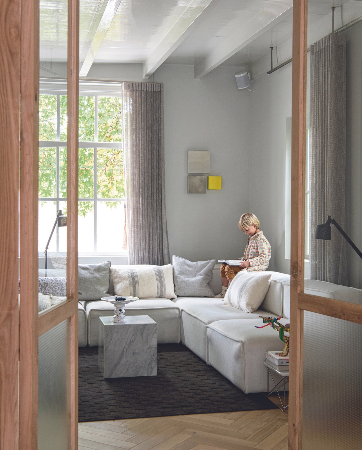 Tweedehands bank BoConcept, marmeren salontafel handgemaakt in Mexico, schaal Hollandsche Waaren, bijzettafel Vitra, kunstobject uit Italië, vloerkleed Vincent Van Duysen, kussen links Moooi, gestreepte kussens Household Hardware, effen grijze kussens Studio Zetel, lampen Vipp, wandobject Laura de Wilde, gordijnen Hakkert, eiken parketvloer Fairwood. Overig onbekend. vtwonen 03-2024 | productie Insidehomepage | styling Esther Loonstijn | fotografie Louis Lemaire