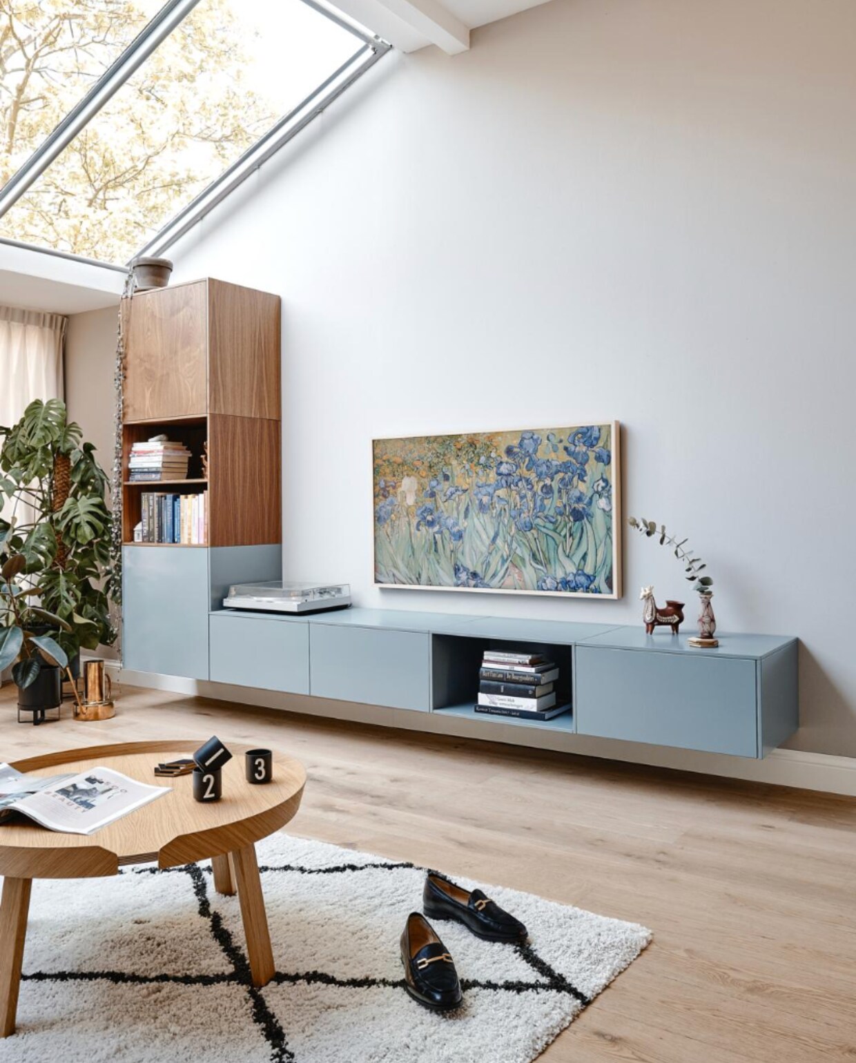 Muurverf Ammonite van Farrow &amp; Ball. Wandkast NoNoo in donker hout en verfkleur De Nimes van Farrow &amp; Ball. Platenspeler van Maartens vader. Televisie The Frame van Samsung met eikenhouten lijst en Van Goghs Irissen als achtergrond. Peruaans lamabeeld van Maartens ouders. Zwarte plantenpot Ferm Living, gieter Divan Tivoli, vloerkleed Benuta, salontafel Muuto, kopjes Design Letters. Loafers Unisa. vtwonen 05-2022 | productie CocoFeatures | fotografie Roos Oosterbroek