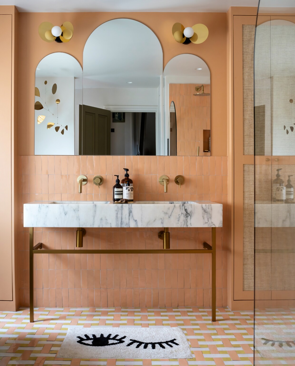Vloer- en wandtegels Mosaic Factory, muurverf Faded Terracotta van Farrow &amp; Ball, behang op kastdeuren Phillip Jeffries, bad vintage, wastafelmeubel Lusso Stone, spiegel ontworpen door Charlotte Lilford, wandlampen Ilios van Atelier Areti, kranen Just Taps, vloerkleed Urban Outfitters, kruk in douche Butterfly van Vitra. vtwonen special 131-2024 | productie Photofoyer | fotografie Benedicte Drummond | styling Fiona Evans