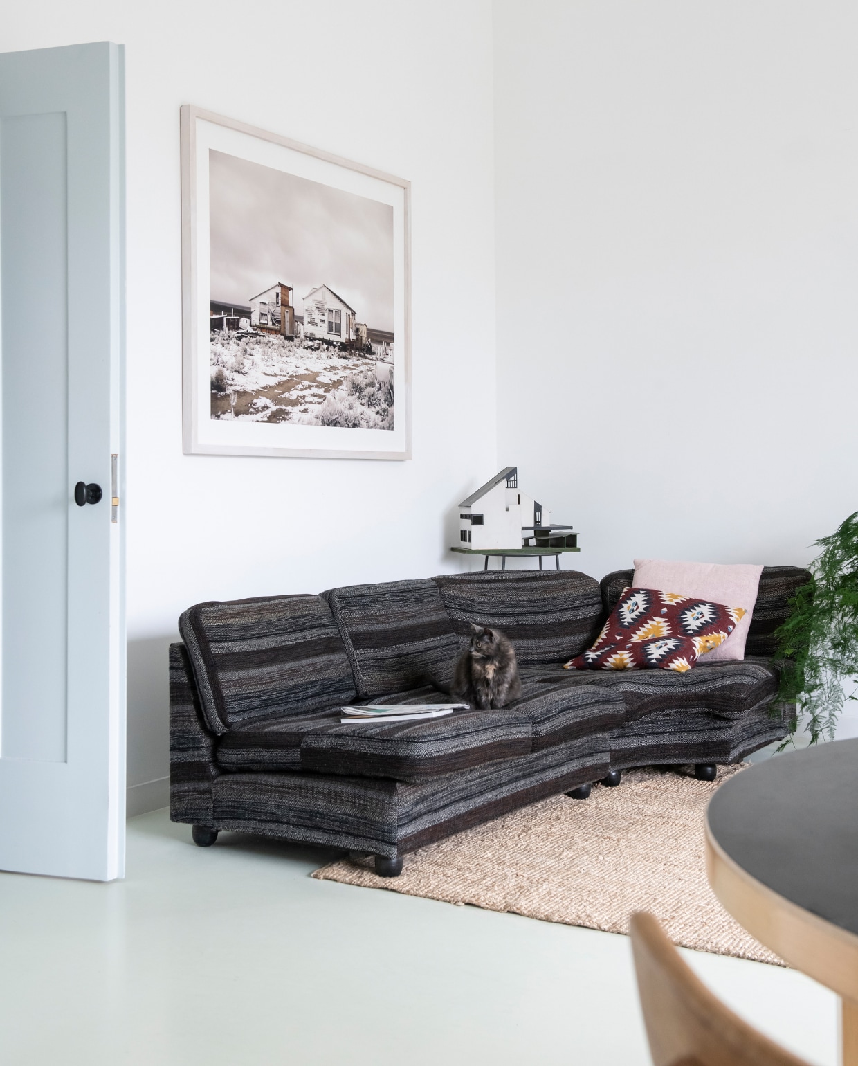 'Deze foto van Roderik Henderson hing bij mijn ouders thuis. Zij gaven hem mij cadeau toen ik hier ging wonen.’ Jaren 70 Artifort bank gekocht op Catawiki. Roze kussen Linum. Ikat-kussen en vloerkleed Ikea. Hoog stalen tafeltje Wereldwinkel met een maquette van ouderlijk huis. vtwonen