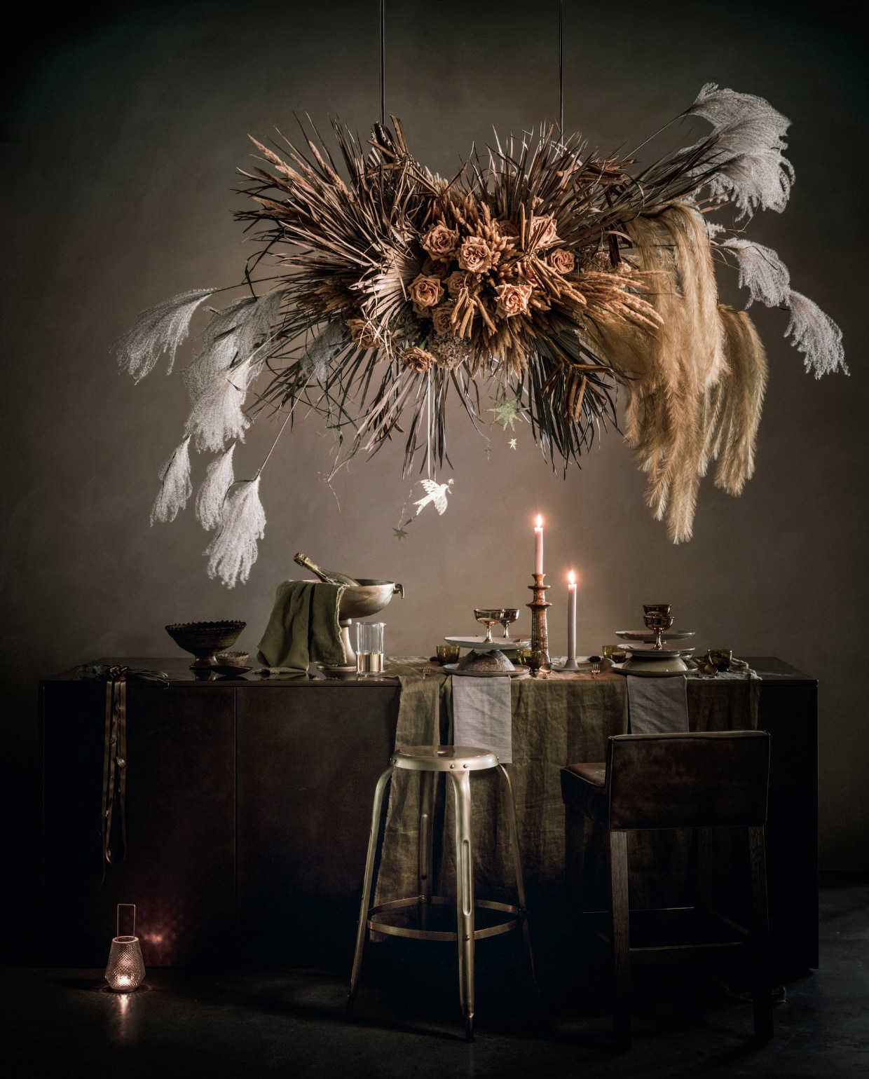 de locatie waar deze productie is gefotografeerd; Studio Piet Boon, die gespecialiseerd is in op maat gemaakte totaalconcepten voor interieur en exterieur, van schets tot styling, tafel Olle 180x160x76 cm (lxbxh) € 6600,-, zwarte stoel Jane vanaf € 1977,- (pietboon.nl). Bruine houten stoel Cherner € 1054,- (edha-interieur.nl). Zwarte stalen spijlenstoel € 2050,- (covanderhorst.nl). Zwarte glazen van Salt&amp;Pepper set van 4 € 24,95, zwart bestek Amefa vintage 16-delig € 35,75, zwarte servetringen van Broste Copenhagen per 6 € 32,99, zwart dienblad van HKliving, 25x45 cm € 34,95, groot zwart dienblad van HKliving, 15x55 cm € 27,10, hoge stoel J110 van Hay € 259,- (vtwonen.nl). Kleine vaas op keukenblad € 35,-, grote vaas op keukenblad € 40,- (101cph.com). Bruin linnen tafelkleed 145x250 cm € 39,99, glazen bakjes € 7,99, bruine servetten set van 2 € 9,99, glazen kan € 19,99,- kleine glazen per stuk € 3,99 (hm.com). Macarons per 8 € 11,50 (toutpatisserie.nl). Champagnekoeler € 115,96, zwarte fles champagne € 93,95 (debijenkorf.nl). Lampenkap € 85,- (householdhardware.nl). Muurverf kleur Driftwood 2,5 dl € 15,- (bauwerkcolour.com). Overig privébezit. v.twonen 12-2019 | styling Liza Wassenaar | fotografie Sjoer Eickmans | assistentie Martine Amama &amp; Rita Wijnhout | bloemenstyling Judith Slagter