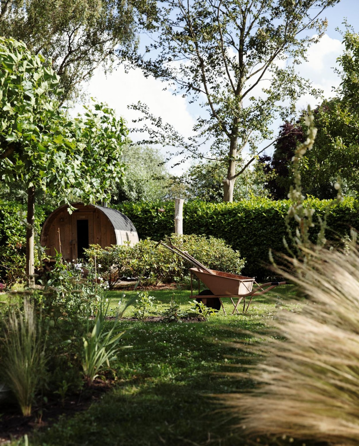 Sauna van Barrelsauna. Taxus- en laurierhagen en een wand van bamboe vormen de erfafscheiding, alles blijft groen in de winter. In de border bij de sauna staan rododendrons. vtwonen Tuin 09 | styling Ilona Jongepier | fotografie Dana van Leeuwen