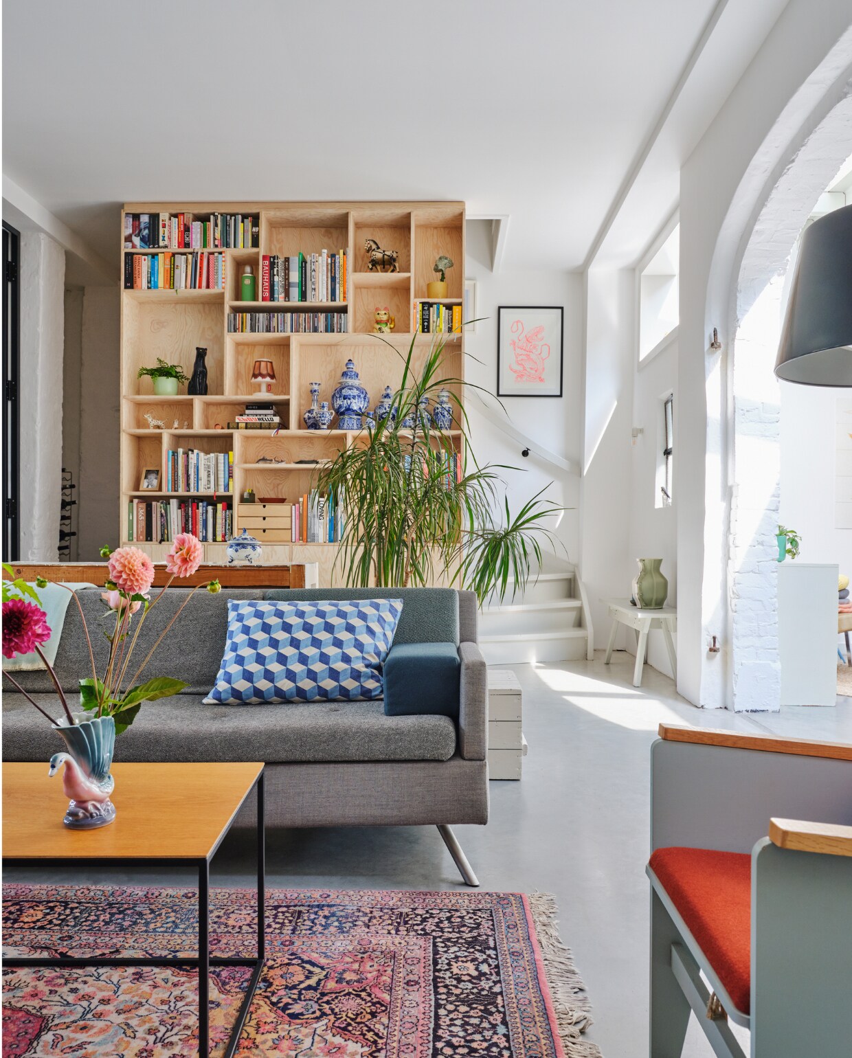 Bank Lot Studio Parade via Vrienden. Geometrisch kussen OXO. Salontafel eigen ontwerp. Fauteuil Katrijn van Floris Hovers via Vrienden. Vloerkleed vintage. Kastenwand op maat gemaakt van Pools grenenhout. Ingelijste prent Trobbies. Wit bankje Piet Hein Eek met daarop de Carter Vase van Floris Hovers via Cor Unum. Overig onbekend. vtwonen special binnenkijken 2022-131 | fotografie Rene van der Hulst | styling Marloes Wolfs | tekst Caroline Hülsenbeck