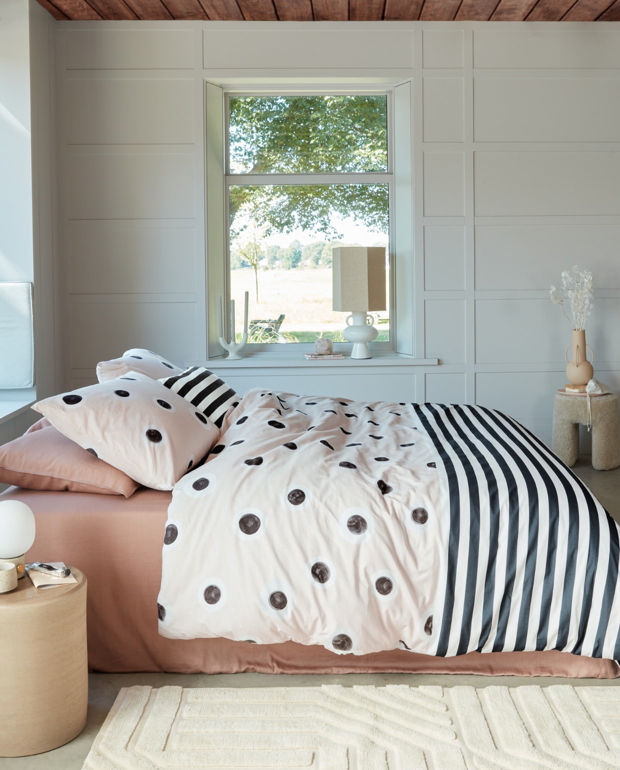 Katoenen dekbedovertrek Stripe and Eye, 140x200/220 cm € 59,95, 200x200/220 cm € 109,95, 240x200/220 cm € 119,95, katoenen kussen Stripe and Eye, 50x50 cm € 44,95.M.m.v. vtwonen.nl (kussenhoezen en dekbedovertrek gebruikt als onderlaken in Earth Pink van vtwonen), loods5.nl/design (stenen kruk, tafellamp met kap), loods5.nl (vloerkleed), designtales.nl (tafellamp), letoile.store (mok), sissy-boy.com (kandelaar), polspotten.com (vaas). Overig privébezit. vtwonen 04-2023 | productie tanja saarberg | styling danielle verheul | fotografie richard smit