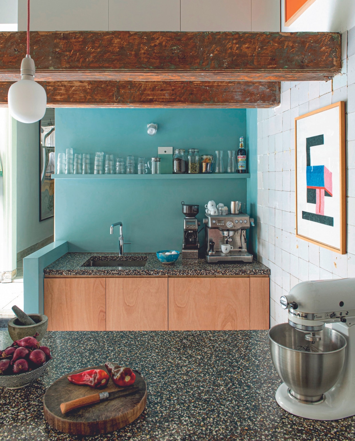Keuken gemaakt door Job van multiplex en een op maat gemaakt blad van terrazzo. Koffiemachine en koffiemolen Sage. Schaaltje zelf gekleid, kraan Quooker, wandlamp Hornbach, kunstwerk Nathalie Du Pasquier, hanglamp Snoerboer, mixer KitchenAid. Vijzel en fruitschaal van een toko. Muurverf Piet Hein Eek Hotel Blue van Lacq. Overig onbekend. vtwonen 04-2024 | productie De Binnenkijkers | styling Jeske Weel | fotografie Caroline Coehorst