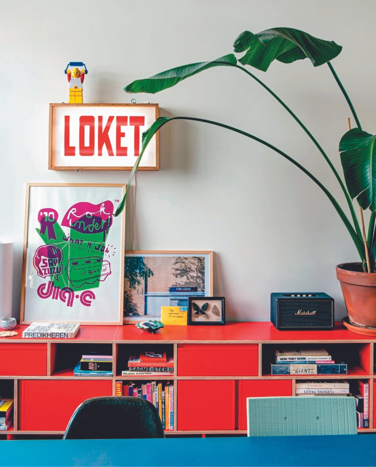 Lichtbak met winkellogo Loket gemaakt door Job. Foto Frank Hanswijk, kast Tylko, bluetoothspeaker Marshall, tafel Muller Van Severen, kuipstoel Vitra, blauwe stoel Ikea. Overig onbekend. vtwonen 04-2024 | productie De Binnenkijkers | styling Jeske Weel | fotografie Caroline Coehorst