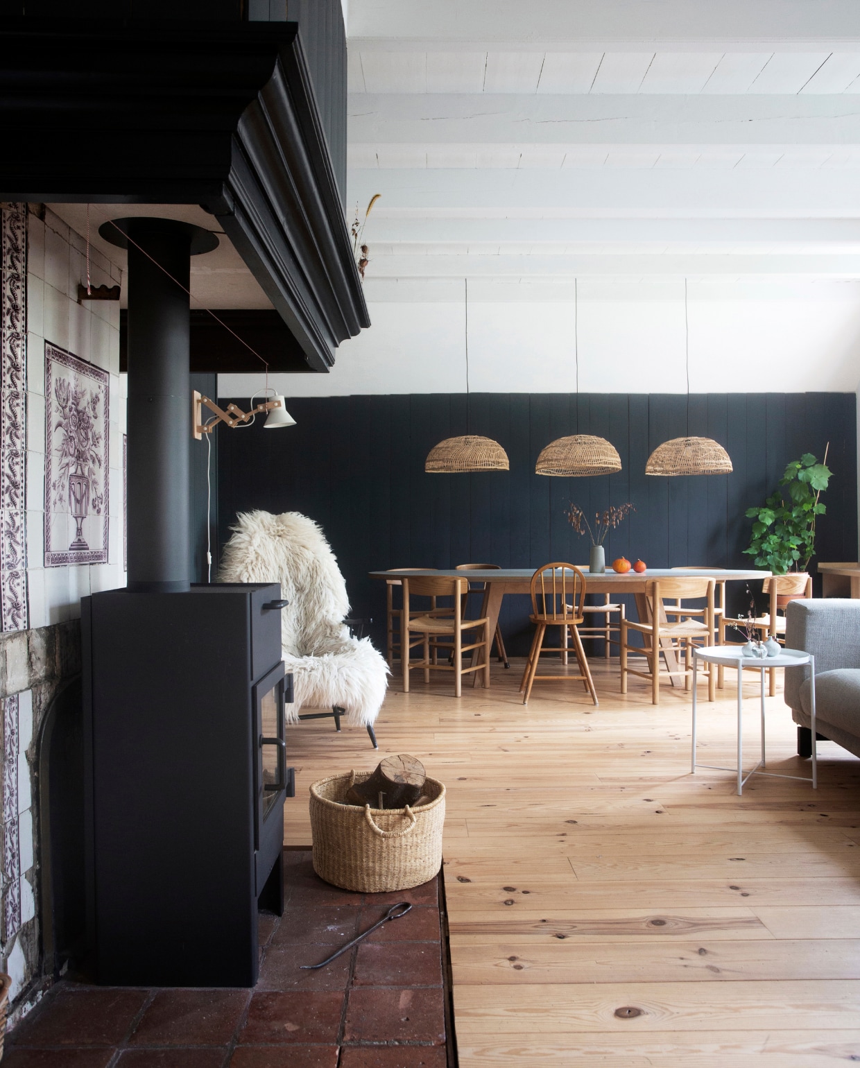 Muurverf Black Blue van Farrow &amp; Ball. Tafel ARP Design. Stoelen replica’s van Borge Mogensen’s J39 via Swivel UK. Kinderstoelen marktplaats.nl. Krukje Hema. Lampen HKliving. Grenenhouten vloer, afgelakt met Skylt, via Wood and Stones. De monumentale tegels bij de houtkachel die ‘ingelijst’ zijn met de zwartgeverfde houten vloerdelen. vtwonen 13-2019 | fotografie Jeltje Fotografie