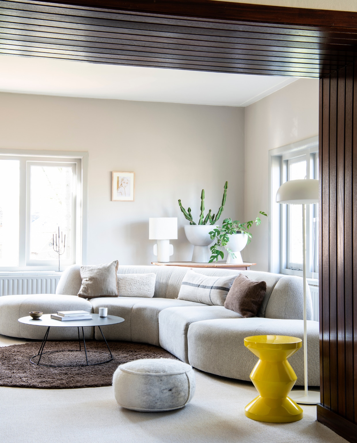 Bank HKliving. Crème kussen, kussen met streep van Ferm Living en witte tafellamp Anne-Marie Wonen. Wit, rechthoekig kussen Karwei. Bruin kussen Tell me more van Jet At Home. Salontafel en kandelaar K’willeminhuis via Anne-Marie Wonen. Vloerkleed Tapeso. Witte poef Jacobien Life &amp; Style. Bloempotten HKliving via Eijerkamp. Kunstwerk Tiny Stories. Gele kruk Zig Zag Pols Potten. Vloerlamp Ikea. Aardewerken kom op salontafel Muubs via Passie Wonen Soest. Mok Xenos. vtwonen special binnenkijken 03-2021 | productie Insidehomepage | styling Esther Loonstijn | fotografie LouisLemaire