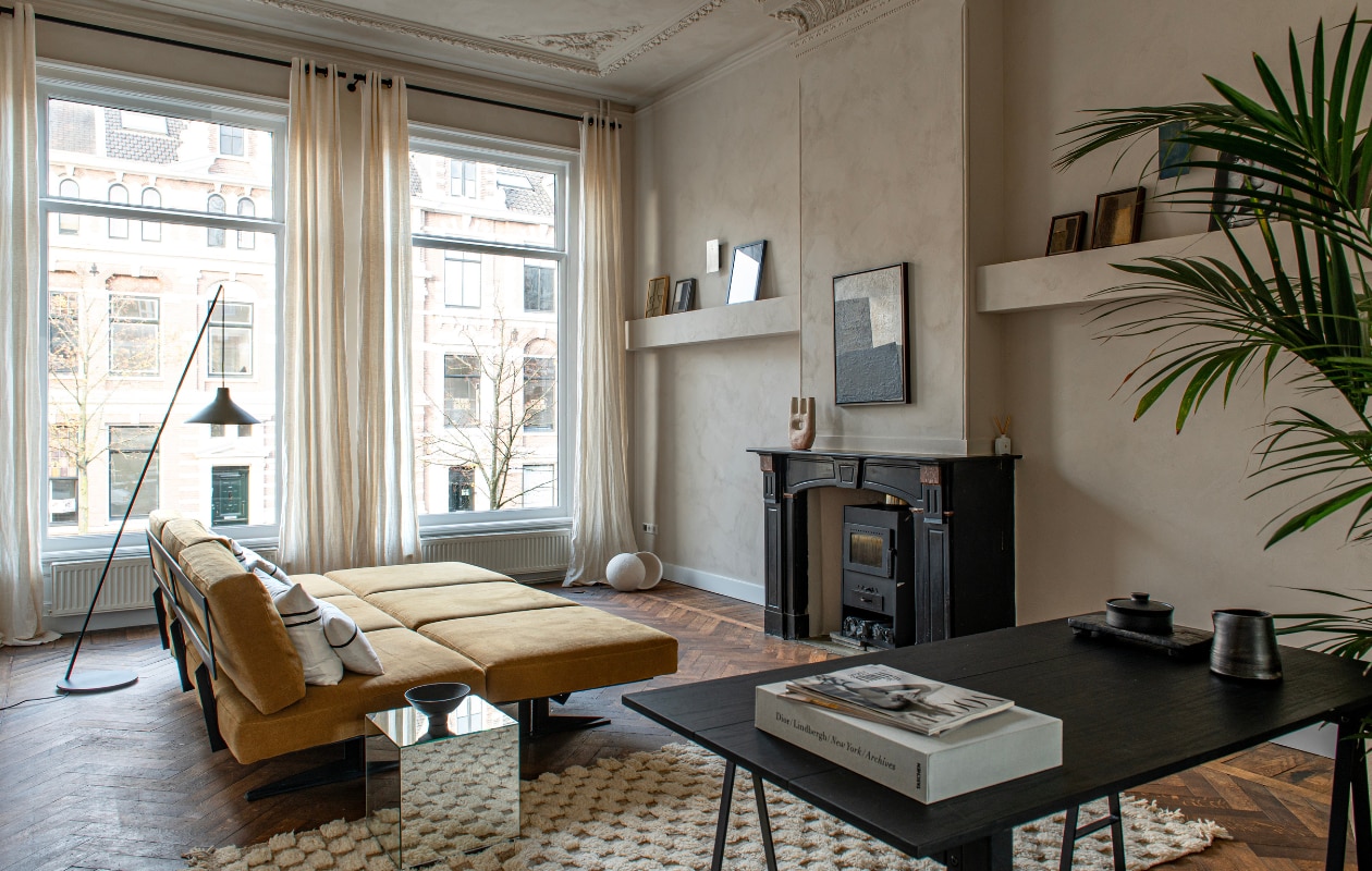 Eilandbank Serax, tafel, kussens, kunstwerk op schouw, alle lampen, muurverf Mallorca van We Are Wow Makers, handgemaakte schaal en karaf van Trudy Suweijn en Marmijn van de Vate, alles via JAS. Vloerkleed zelf meegenomen uit Marokko. Kunstwerken Eva Sanders, behalve helemaal links Edith Beurskens. Spiegelkubus onbekend vtwonen binnenkijken special 131-2024 | productie De Binnenkijkers | styling Jeske Weel | fotografie Caroline Coehorst