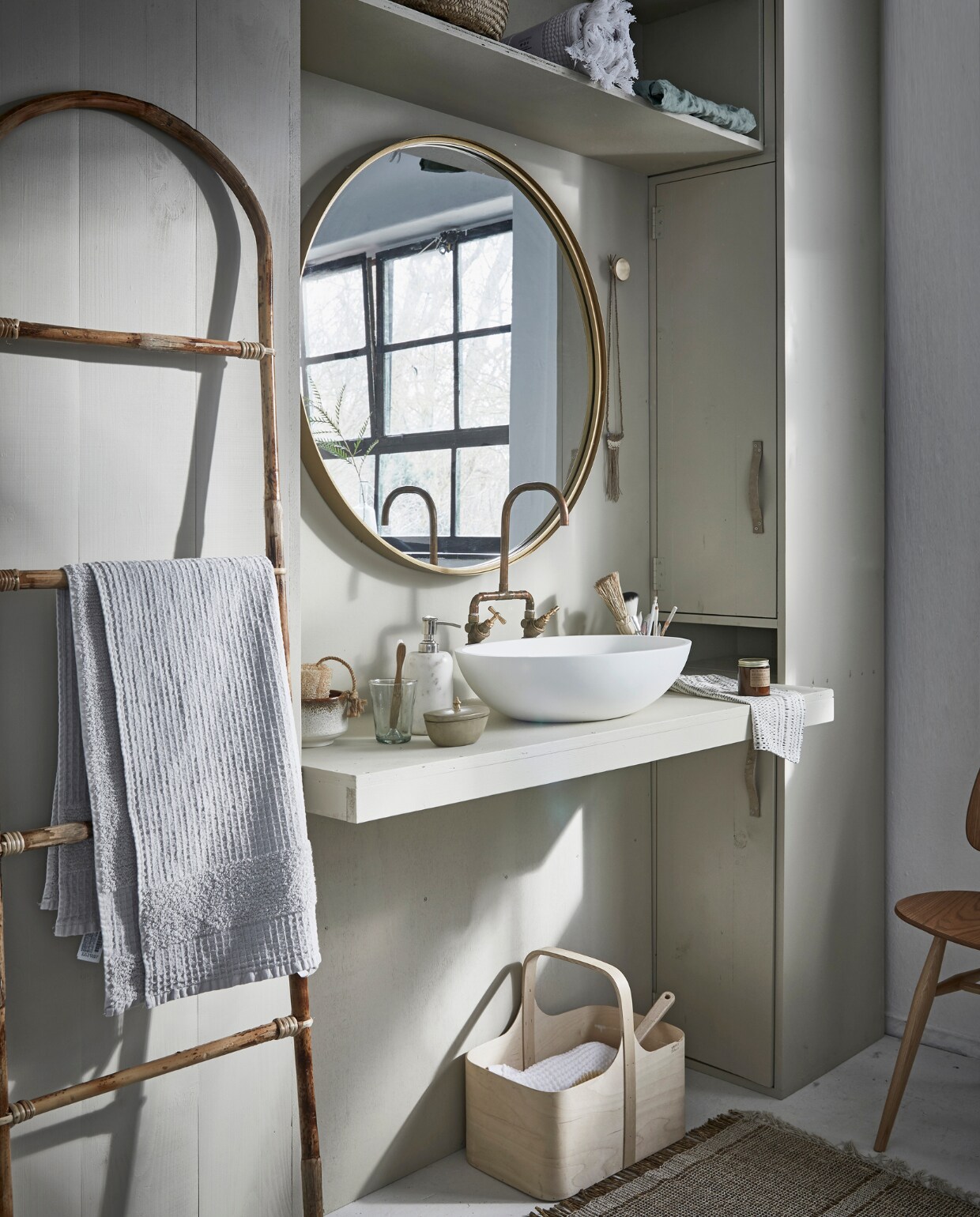 Grote ronde spiegel Ø 80 cm € 249,-, marmeren zeeppomp € 41,- (Nordal). Bamboe ladder € 54,05, vloerkleed 60x90 cm € 23,65 (Madam Stoltz). Witte wafeldoek € 49,95 (De Weldaad). Stoel Butterfly van Ercol € 625,- (De Machine- kamer). Berkenplex opbergmand 25x40x36 cm € 89,50 (Nordic New). Grijze handdoek 90x150 cm € 35,99(Zara Home). Waskom Girona, 57x40x15 cm € 381,- (Ton Scholten). Kraan € 75,- (Jan van IJken Oude Bouwmaterialen). Tadelakt zandkleurig potje met deksel € 19,95 (MaisonNL). Bureaulamp € 95,-(Vint. Amersfoort). Glas € 3,95, linnen doek in opbergzak € 75,-, witte opgerolde wafeldoek € 45,- (De Weldaad). Zandkleurig met bruine kom € 39,99, messing muurknop van Ferm Living € 20,-, geurkaars in bruin glazen potje € 16,- (Six and Sons). Rieten mand in kast vanaf € 9,99 (H&amp;M Home). Badborstel € 8,95 (Dille &amp; Kamille). De kast is geschilderd in de kleur Bone van Farrow &amp; Ball per 0,75 liter € 44,- (De Ru). De muur is geschilderd in de kleuren Egg White en Light Grey van vtwonen, per liter € 18,95, per 2,5 liter € 32,95 (Karwei). vtwonen 05-2018 | styling Cleo Scheulderman | fotografie Jeroen van der Spek
