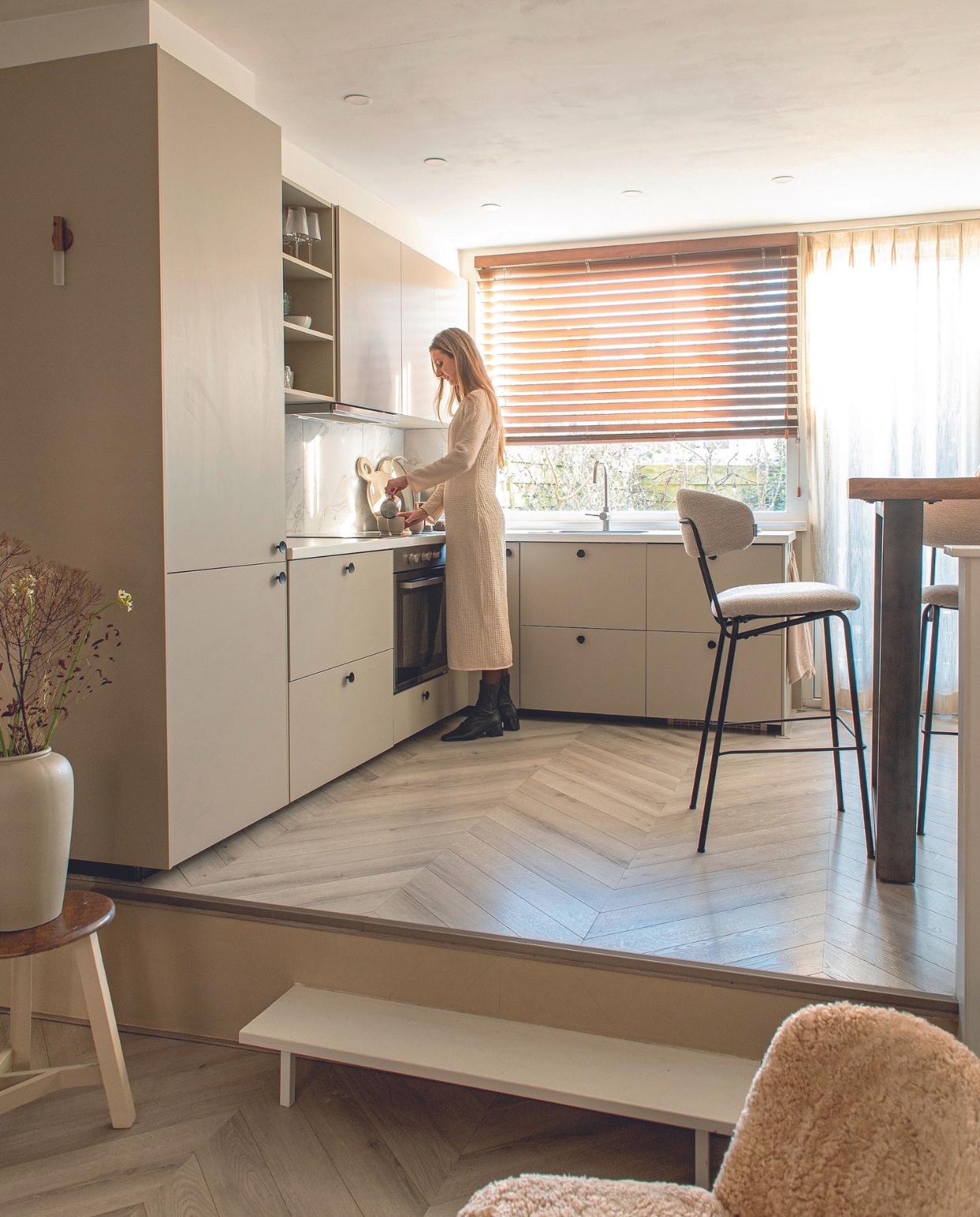 Kastfronten Havstorp van Ikea in beige, zijpanelen geverfd in NCS S 3005-Y20R, meubelknoppen Zara Home. Kruk en vaas kringloop. Wandlamp Temu, bartafel Eleonora, barstoelen Label51, jaloezieën Veneta, gordijnen Guus van Kwantum, fauteuil Chisel van Hay. Overig onbekend. vtwonen 04-2024 | productie De Binnenkijkers | fotografie Caroline Coehorst | styling Jeske Weel