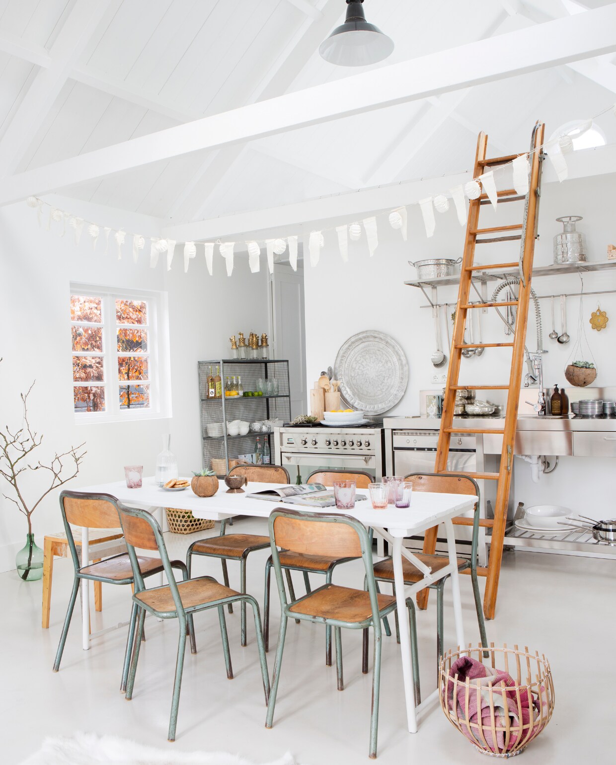 Slinger van Sukha Amsterdam, lampionnensnoer van Nordal en hertenkop via L'etoile.store. De industriële lamp kocht ze bij Hal72, stoelen van Vivre Authentique, tafel van Combitex. Houten borden van HK Living. De glazen met bloemen zijn van Pols Potten. De andere glazen zijn van Bitossi, schaal van From Africa with Love, flesvaas en fotolijst van sloophout, alles via l’Etoile Conceptstore. Bank van Ikea. Kruk van Piet Hein Eek. Bamboe rolgordijnen van Leen vtwonen 12-2015 | fotografie Jeltje Janmaat | styling Elisabeth Borger