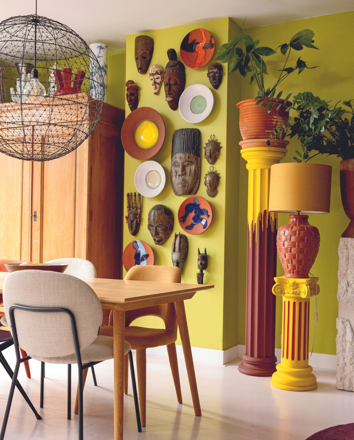 Muurverf Acid Green van Farrow &amp; Ball, kast familiestuk, tafel &amp;Tradition. Stoelen en hanglamp Polspotten, rode vaas Studio Roderick Vos, koraalvaas Norman Trapman, borden Jan Snoeck, bloempot tuincentrum. Overige vazen, maskers, tafellamp en schaal van rommelmarkten en uit kringloopwinkels. Zuilen Marktplaats. vtwonen 04-2024 | styling Ilona Jongepier | fotografie Dana van Leeuwen