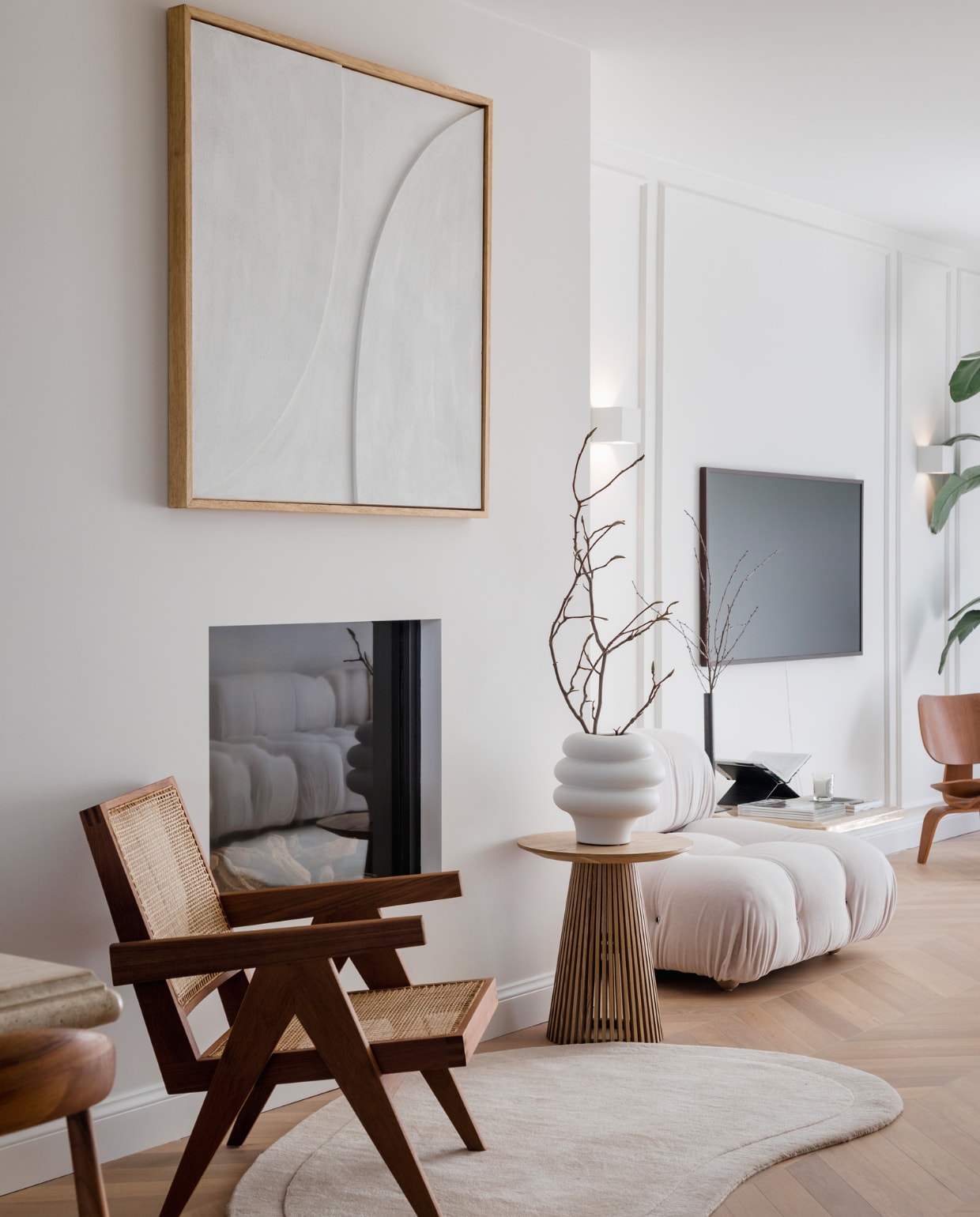 Muurverf Slate I van Paint &amp; Paper Library via verfhandel van Laar. Eikenhouten vloer gelegd in Hongaarse punt via BVO Vloeren. Kunst Amy Maye Art, lattentafel Kwantum, vloerkleed Westwing, rotan loungestoel van Pierre Jeanneret via Object Embassy. Bank Camaleonda sofa in kleur Licata 2165102 van Mario Bellini voor B&amp;B Italia via Studio van ’t Wout. Vaas en takken H&amp;M Home, televisie Samsung The Frame. vtwonen binnenkijken special 131-2024 | fotografie Corine Hoge Bavel-Jansen