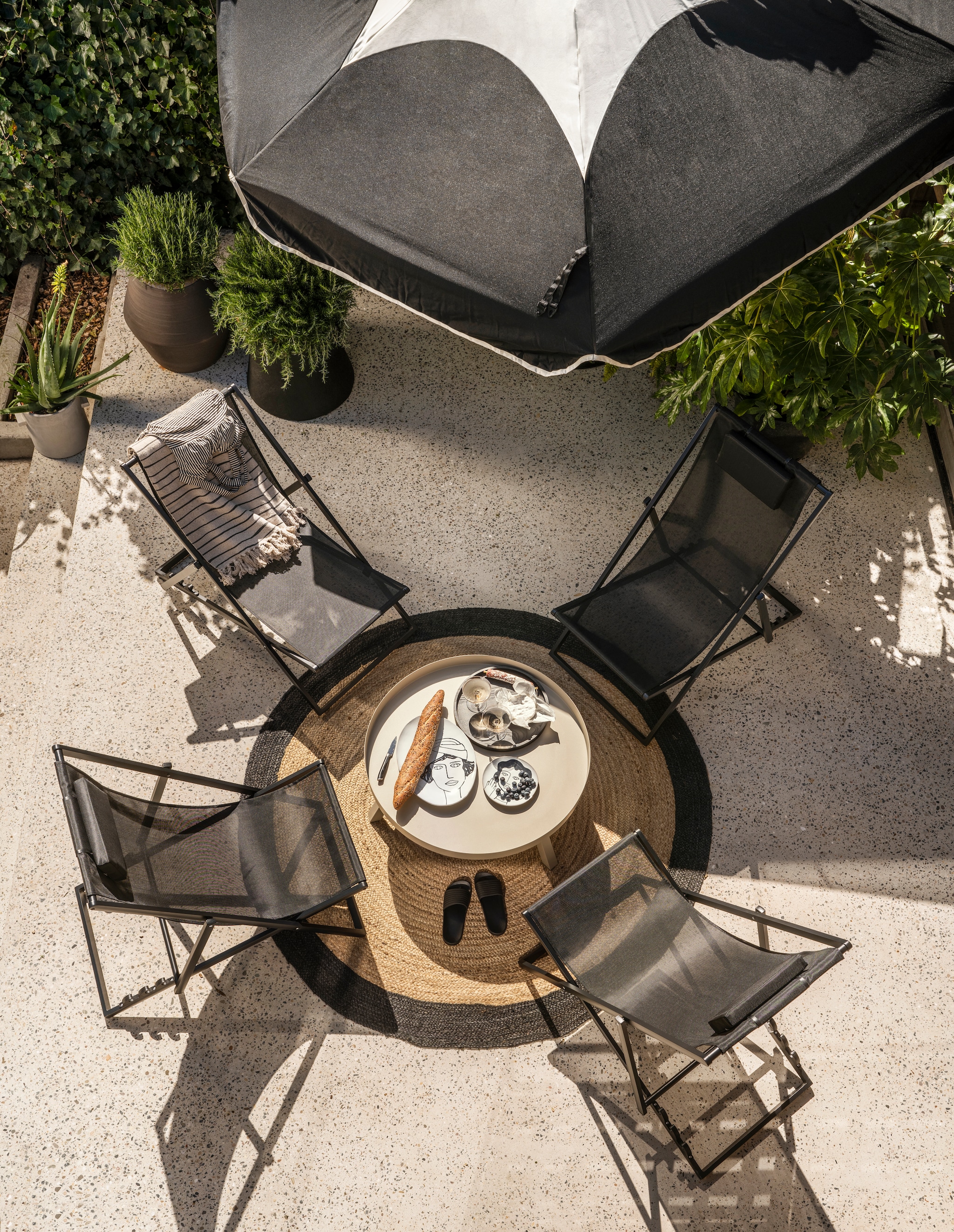 Strandstoelen Esper van Exotan, aluminium en textiel, 61x102x74 cm (bxdxh) per stuk € 109,-, metalen salontafel Sunny van Woood, 80x35 cm (Øxh) € 99,95, houten dienblad € 99,99, borden La Mère vanaf € 21,- en bloempotten van Serax vanaf € 381,-, plaid Eia van Bloomingville, gerecycled katoen, 160x130 cm € 23,99, champagneglazen Ripple van Ferm Living, set van 2 € 35,- (vtwonen.nl/shop). Polyester parasol Sunshady, 300 cm (Ø) € 399,- met stalen parasolvoet Base € 399,- (fatboy.com). Juten vloerkleed Rondo, 180 cm (Ø) € 85,- (hetkabinet.nl). Badpak (marliesdekkers.nl). Slippers (hema.nl). Overig privébezit. vtwonen 07-2024 | fotografie Stan Koolen | styling Marianne Luning, Kelly van Gendt