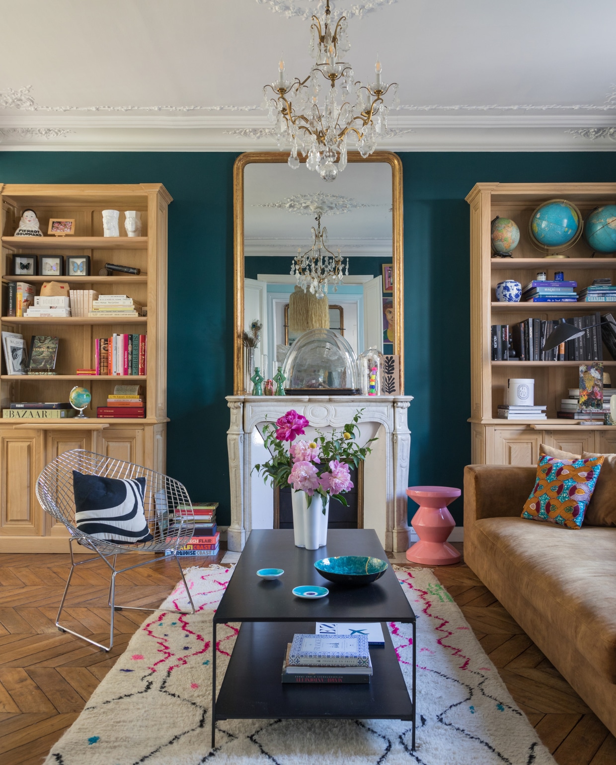 Muurverf Hague Blue van Farrow &amp; Ball. Kleed Asamaya, salontafel La Redoute, vaas Iittala, schaal Véronique Vindevoghel, kopjes uit Griekenland. Bank Parnac, Bertoia-stoel vintage, kroonluchter van veiling. Kussens Fs Home Collections. Wereldbollen rommelmarkt. Overig onbekend. vtwonen binnenkijken special 131-2024 | productie Marie Maud Levron Creations | fotografie Cécile Perrinet Lhermitte