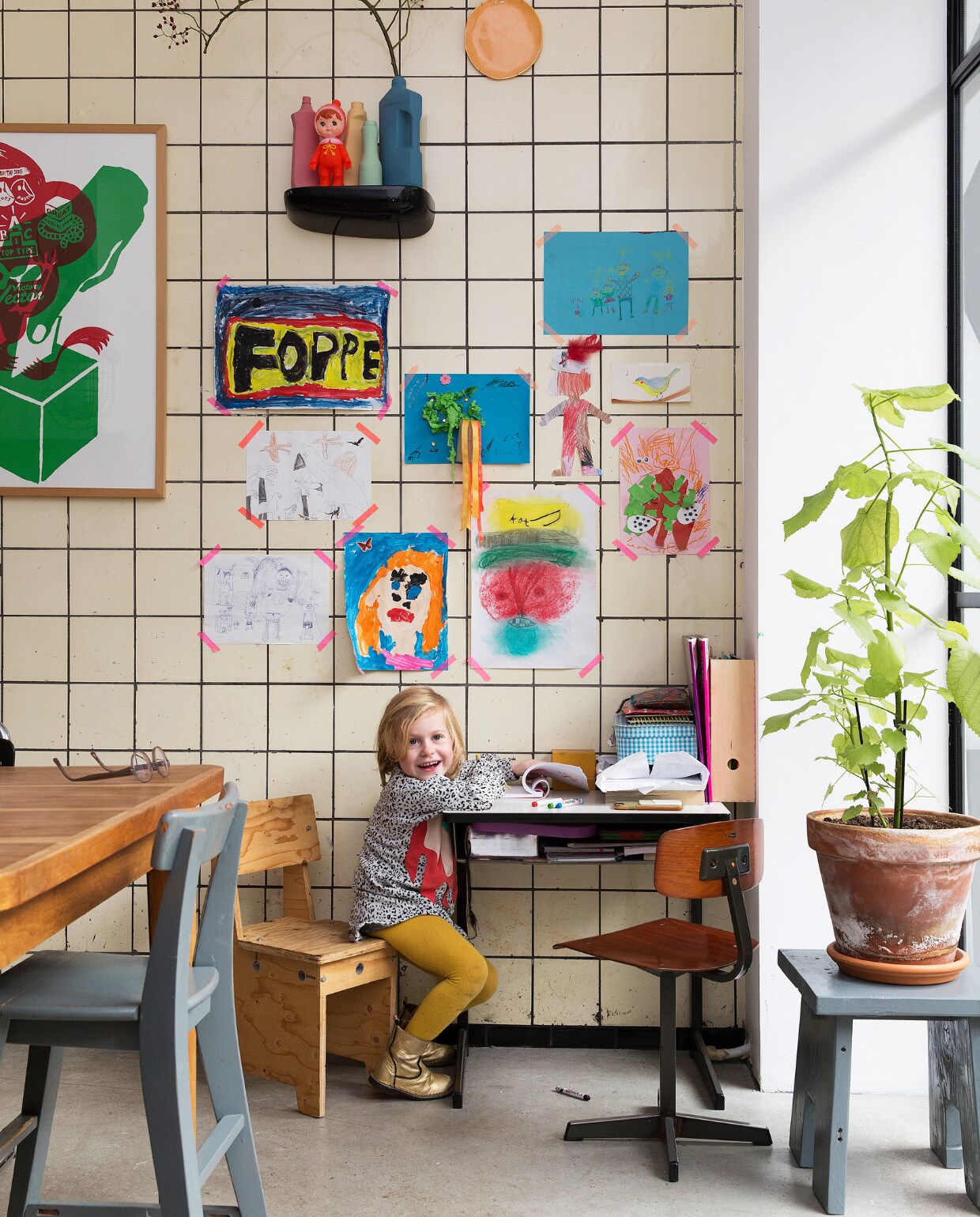 Aan de muur knutsels van de kinderen, bordjes van &amp;klevering, vazen van Foekje Fleur en een schilderij van Boxie1970. Lamp van Neef Louis. De grijze bank heeft Job, naar een voorbeeld in vtwonen, zelf gemaakt. Omdat er nog hout over was, maakte hij ook een bijpassend krukje. Houten kinderstoeltje is van Piet Hein Eek. Omdat buiten toevallig een beugel aan de muur hing, besloot het stel de oude racefiets van Job daaraan te hangen. En klaar was de geïmproviseerde – droge - opbergplek.Zwarte wandplank van Vitra, buitenbank van Leen Bakker. vtwonen binnenkijken special 121-2017 | styling Emmy van Dantzig | fotografie Jansje Klazinga