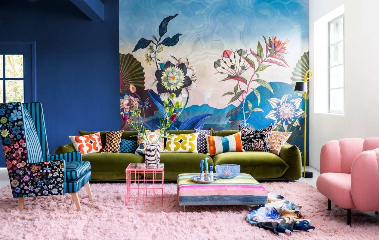 Paneel met behang Atlantis Aube van Christian Lacroix voor Designers Guild, 300x350 cm € 927,- (wva.nl). Blauwe muurverf Exciting Night No. 96 van Lab Paint, per liter € 45,- (vestingh.nl). Groene velours bank van Arflex, 96x354x70 cm (dxbxh) € 5709,-, roze fauteuil van Warm Nordic, 95x84x80 cm (bxdxh) € 2190,-, zachtroze hoogpolig wollen vloerkleed van Layered, 250x350 cm € 1090,- (goeds.nl). Multikleurige voetstoel in stof Rayure Chinoise Alchemilla van Designers Guild, 90x90 cm € 1485,-, oorfauteuil Harper Chair bekleed met stoffen van Christian Lacroix voor Designers Guild € 3220,- (wva.nl). Verstelbare vloerlamp € 659,- (hay.nl). Roze staaldraad tafel van Bold Monkey, 41x41x40 cm (lxbxh) € 165,- (boldmonkey.com). Kandelaars vanaf € 14,50, kaarsen van Hay, per 6 € 25,-(vtwonen.nl). Glazen vaas € 85,- (hay.nl). Vintage bord € 25,- (hetgroteavontuur.nl). Blauwe schaal € 39,- (festamsterdam.com). Kussens van links naar rechts: rood geborduurd € 149,-, langwerpig model van zijde, per stuk € 89,- met bloemdessin € 109,-, groen geborduurd € 149,-, alles van Lelievre (loggerewilpower.com), velours streep van William Yeoward € 121,-, bloemen Christian Lacroix voor Designers Guild € 192,-, geborduurd € 132,-, wollen plaid van Designers Guild € 327,- (wva.nl). vtwonen 06-2022 | styling Marianne Luning | fotografie Stan Koolen
