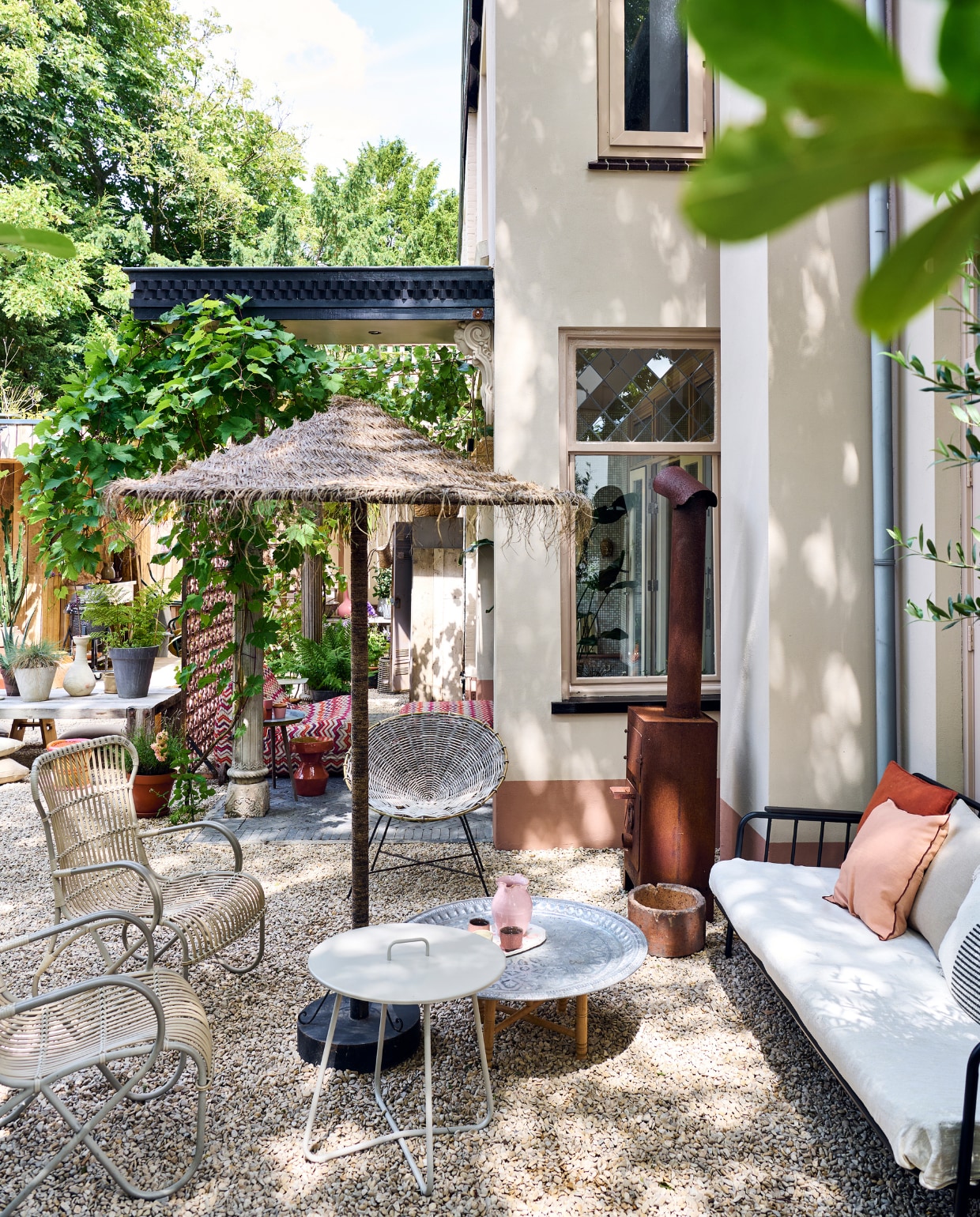 Buitenkachel Weltevree. Tuinbank en witte bijzettafel Kwantum. Tuinstoelen Sissy-Boy, kuipstoel Kave Home, parasol Household Hardware, lage bijzettafel Ottomania, kan souvenir Italië, schaal met kommetjes souvenir Lissabon, kussens H&amp;M Home, betonnen pot Intratuin. Overige zie andere fotobijschriften. vtwonen tuinspecial 10 | styling Liza wassenaar | fotografie Sjoerd Eickmans