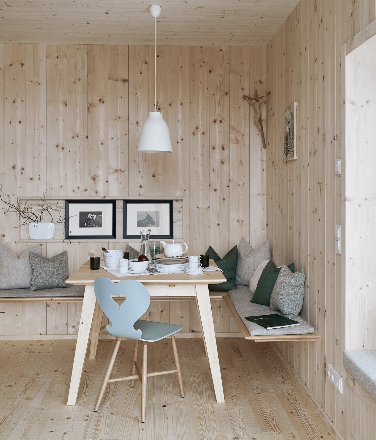 Vurenhouten wandbekleding en vloer. Tafel op maat gemaakt door een lokale timmerman, stoel Trix van Schmidinger Möbelbau. Linnen kussens van Leitner Leinen, wollen kussens van Loden Steiner. Servies Piana van Lambert, hanglamp Caravaggio van Fritz Hansen, ingelijste prints uit een kalender. Herkomst overige items onbekend vtwonen 13-2020 | productie Features &amp; More | styling Wilma Custers | fotografie Krista Keltanen