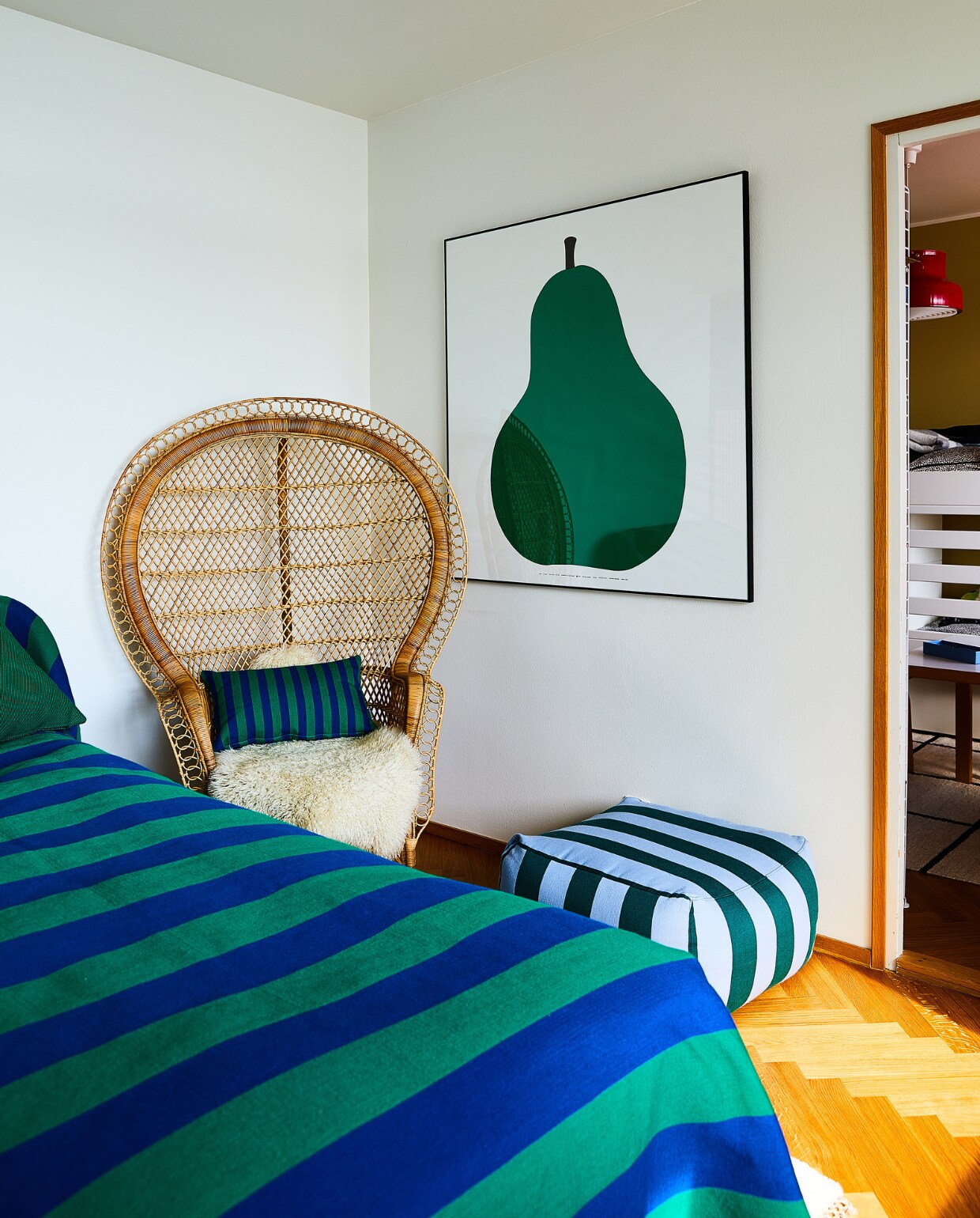 Bed, gestreepte stof van Hakola, poef Hakola, ingelijste peerposter vintage vondst. Overig onbekend. vtwonen binnenkijken special 131-2024 | productie Living Inside | styling en tekst Jonna Kivilahti | fotografie Krista Keltanen