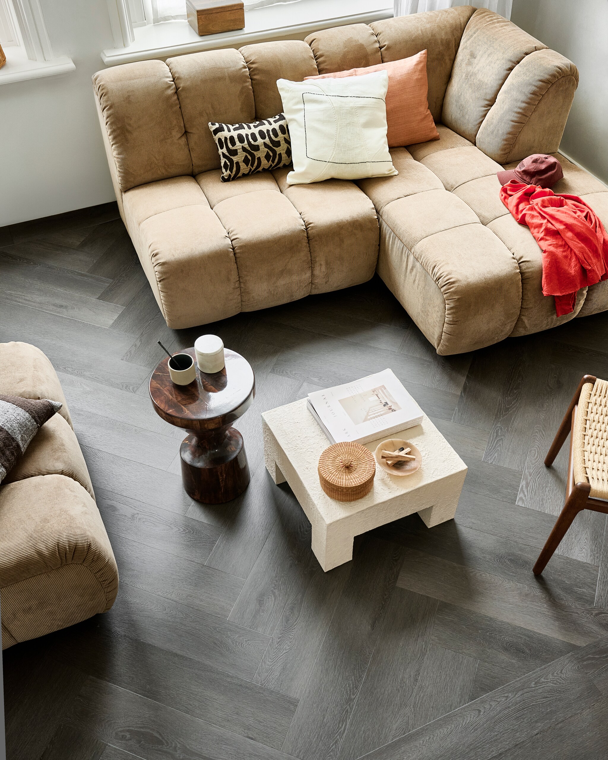 Pvc-vloer Herringbone in Charcoal, 76,5x15,3 cm, dryback per m² € 44,95 en click per m² € 57,95. M.m.v. hkliving.com (elementenbank, bijzettafel, bruin gestreept kussen, beige kussen met motief), urbannatureculture.com (salontafel, kistje, wit kussen met zwarte lijn, roze kussen), vtwonen.nl/shop (stoel Dutchbone).Styling: Marlies Doesvtwonen editie 08 2024 vtwonen 08-2024 | styling Marlies Does | fotograaf Sjoerd Eickmans