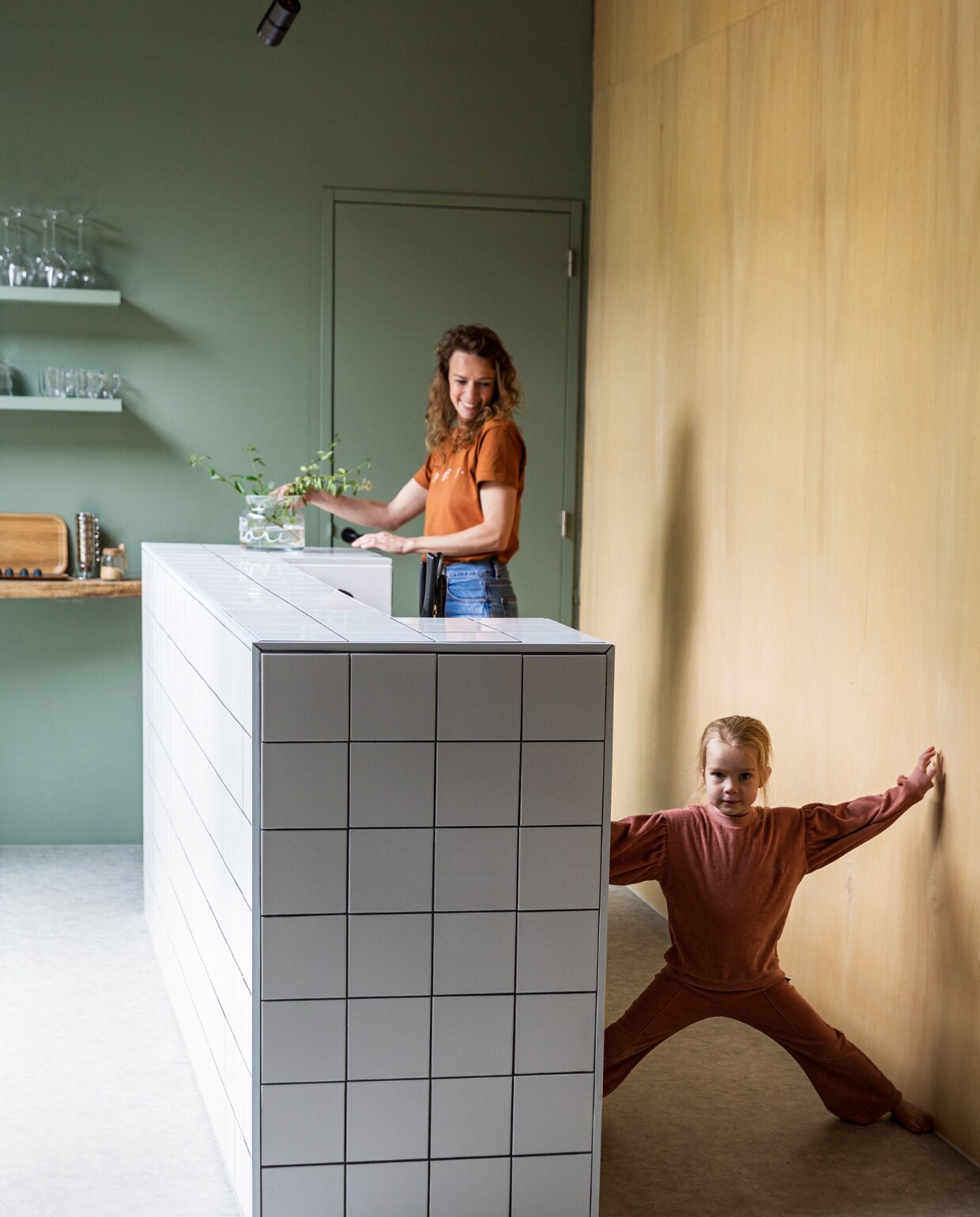 Keukenblok eigen ontwerp maatwerk, afgewerkt met geglazuurde tegels Praxis. Houten wand Okoume platen Bouwcentrum Driessen. Houten schappen koffiebar resthout meubelfabriek, deels geverfd in kleur Geordend van Histor.  vtwonen 01-2022 | styling Ilona Jongepier | fotografie Dana van Leeuwen | visagie Djolien de Kreij