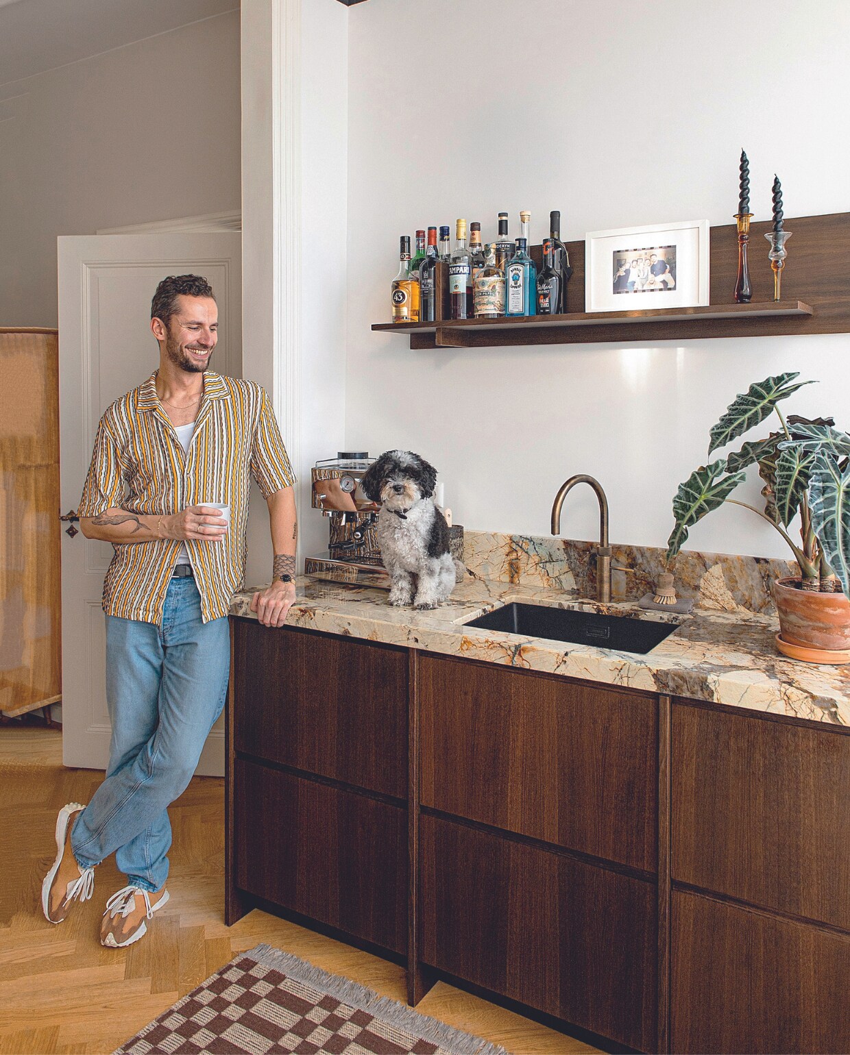 Binnenwerk keukenkastjes Ikea. Frontjes, zijwanden en wandplank Frøpt. Mick plaatste zelf verticale sierlatten tussen de lades. Patagonia kwartsiet keukenblad StoneCenter, kraan Quooker, kandelaars uit Griekenland, duckbill- plafondlamp Marktplaats, plafondverf Off-Black van Farrow &amp; Ball. Overig onbekend. vtwonen 05-2024 | productie De Binnenkijkers | styling Jeske Weel | fotografie Caroline Coehorst