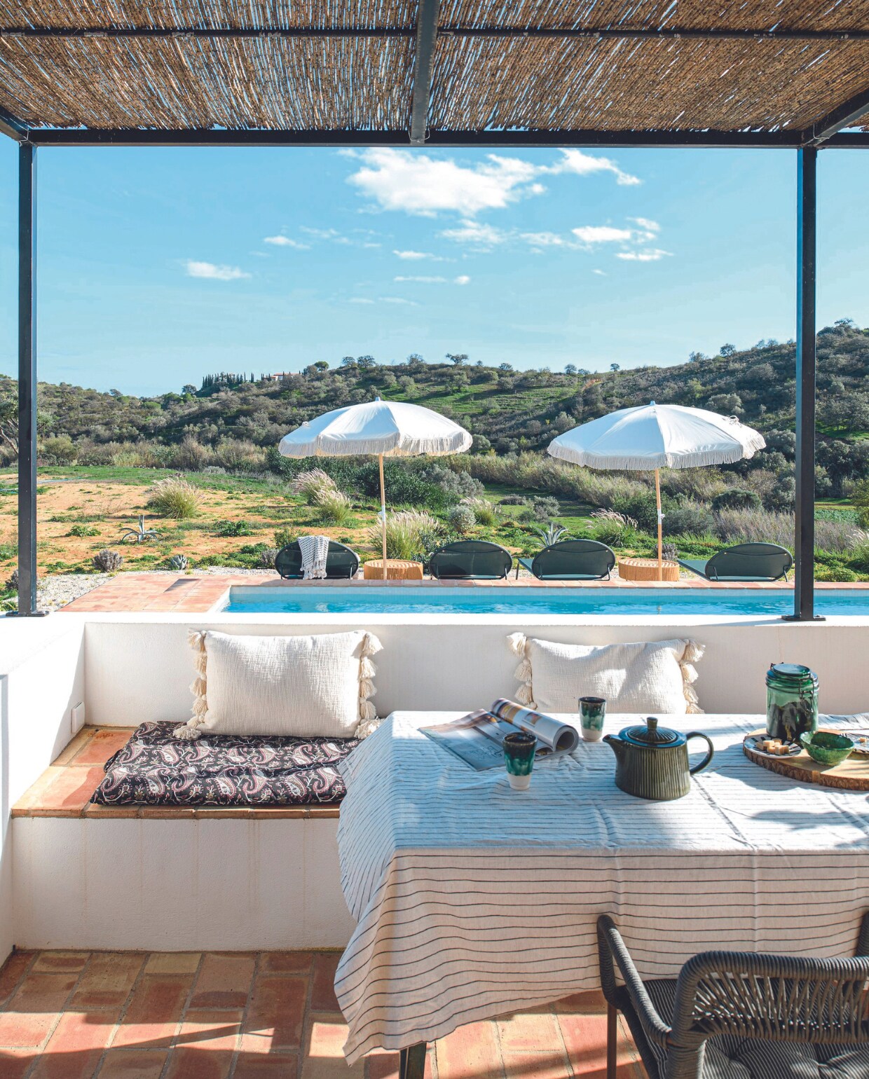 Eettafel La Redoute, ligbedden Habitat, parasols Courant Sauvage, bijzettafels en witte kussens Madam Stolz. vtwonen 06-2024 | productie Inside Homepage | styling Anja Bas Backer | fotografie Louis Lemaire