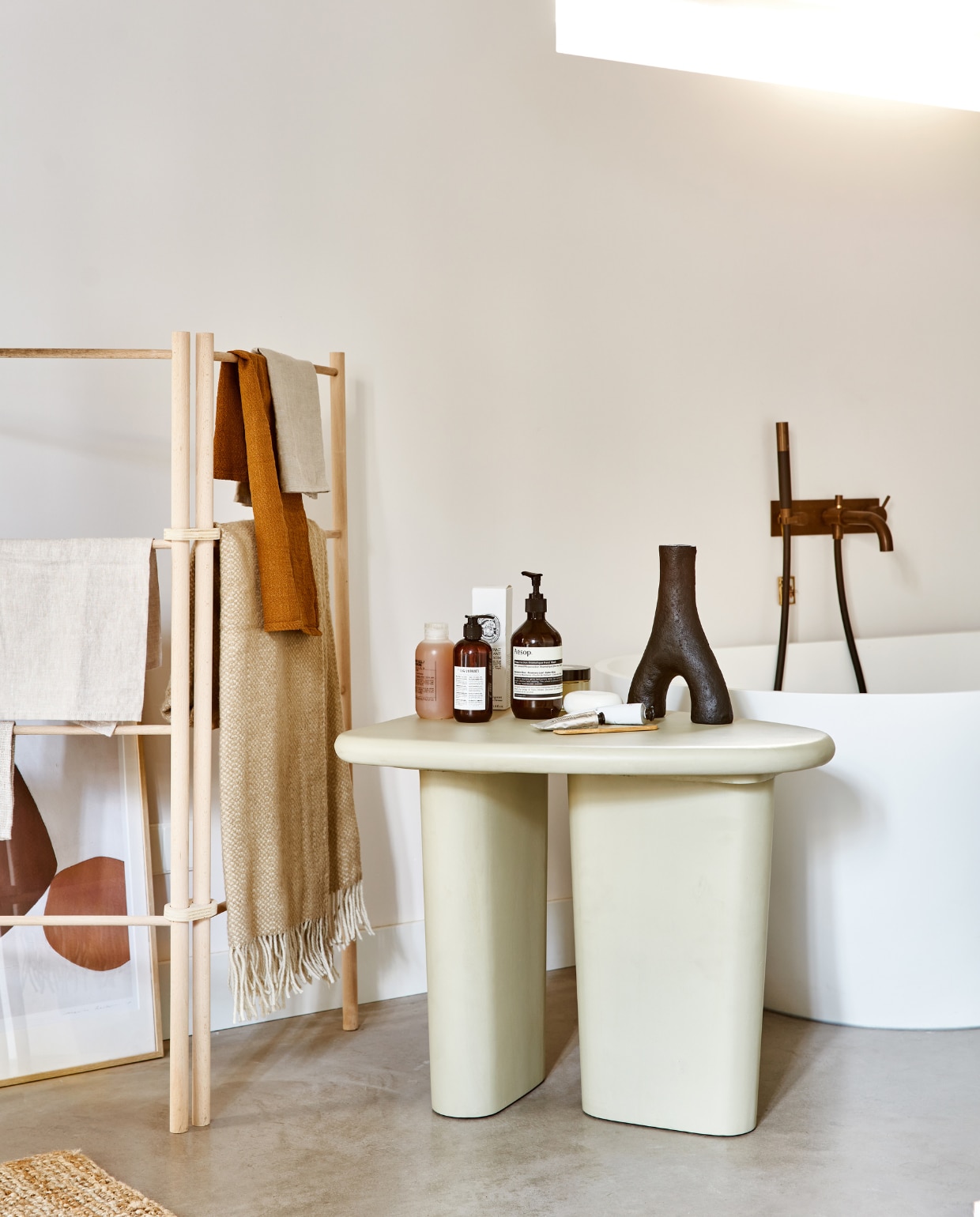 vtwonen collectie (mangohouten bijzettafel Beach in kleur Clay, small 64x51x53 cm (lxbxh) € 319,-, ook verkrijgbaar in medium 80x41 cm (Øxh) € 399,-). M.m.v. pantoufle-design.nl (houten droogrek), vtwonen.nl (artwork Padia van Kave Home, plaid met franje van Silkeborg, zwarte vaas Twig van vtwonen), skins.nl (handzeep, zeep met pompje, tube handcrème), dille-kamille.nl (houten kam). Overig privébezit. vtwonen 02-2022 | productie Tanja Saarberg | styling Marlies Does | fotografie Bart Brussee