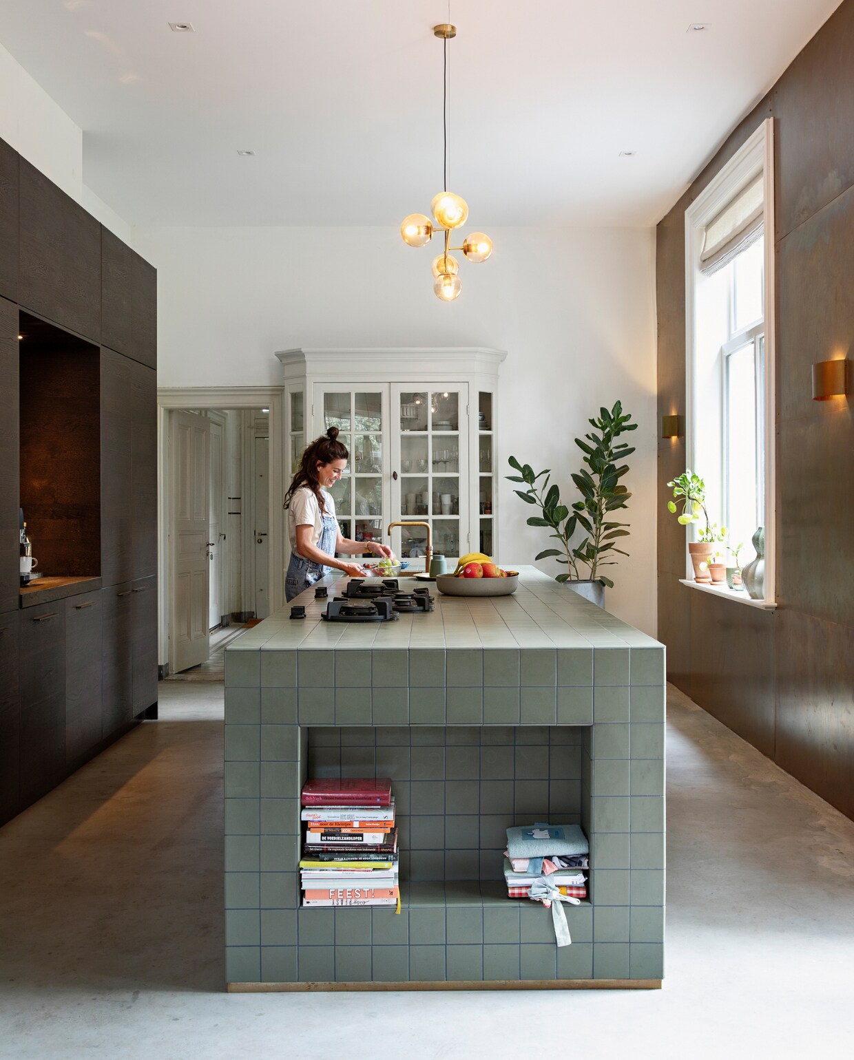 Keuken zelf ontworpen en zelf gebouwd, notenhouten kastjes Kvik, tegels Winckelmans. Lamp LumenXL, messing wand en wandlampen zelfgemaakt met platen van de koperslagerij. Fornuis Pitt Cooking, witte kast originele inbouwkast, vloer gevlinderd zandcement, geïmpregneerd met impregneermiddel voor beton. vtwonen binnenkijken special 131-2024 | styling Ilona Jongepier | fotografie Dana van Leeuwen