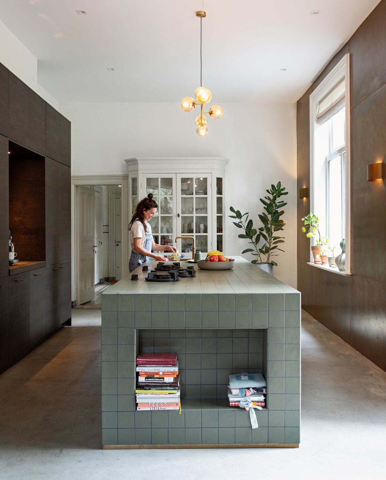 Keuken zelf ontworpen en zelf gebouwd, notenhouten kastjes Kvik, tegels Winckelmans. Lamp LumenXL, messing wand en wandlampen zelfgemaakt met platen van de koperslagerij. Fornuis Pitt Cooking, witte kast originele inbouwkast, vloer gevlinderd zandcement, geïmpregneerd met impregneermiddel voor beton. vtwonen binnenkijken special 131-2024 | styling Ilona Jongepier | fotografie Dana van Leeuwen
