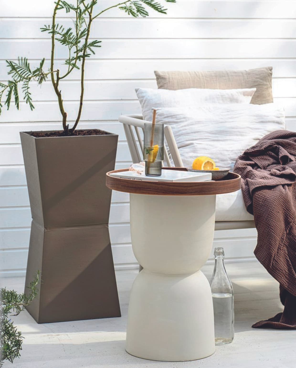 Mimosa boom € 59,95, rozemarijn € 24,95 (bloementuinaandezaan.nl). Aluminium bankelement Menton € 299,- (jotex.nl). Longdrinkglas Ripple van Ferm Living in Smoked Grey, set van 4 € 59,- (thefinestore.com). Parasol Pescara van Human Nature, 180 cm (Ø) € 44,99 (anwb.nl). Beige linnen kussenhoes € 14,99, mousseline sprei, 180x250 cm € 69,99, linnen gordijnen, set van 2 € 84,99 (hm.com). Witte linnen kussenhoes Milk € 19,-(puurlifestyle.com). Houtfineer dienblad Ombonad, 42 cm (Ø) € 34,99 (ikea.nl). Overig privébezit.