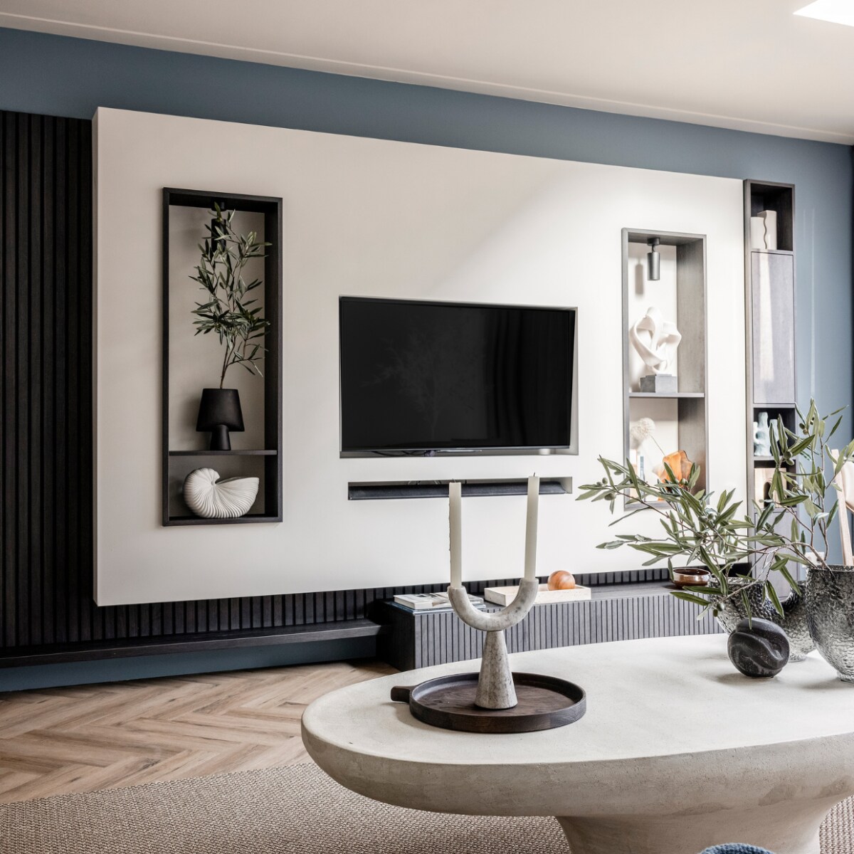 Verf muren bij de tv Denim Drift Flexa, Wandkast van de bewoners, geverfd in Sandy Beach Flexa, Wandmeubel met verticale lattenwand en ledverlichting Meijer Maat Interieurs, Bank Shark in de stof Sabbia 11 cream Eijerkamp, Vloerkleed Luca 6704 Cunera, Salontafel La Nena, Blauw plaid van Malagoon vtwonen, Marmeren siervorm met zware voet Nordal, Rond ornament Eijerkamp, Vazen Eijerkamp, Dienblad Eijerkamp, Kandelaar met twee armen Nordal, Kaarsen Hema, Olijftak 138217 Silk-ka. Overig privébezit Weer verliefd op je huis seizoen 17 aflevering 4 | styling Liza Wassenaar | fotografie Sonja Velda