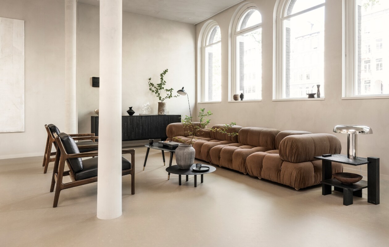 Marmoleum vloer in Kwarts, 200 cm breed, per m² € 50,40. M.m.v. homestede.nl (elementenbank), vtwonen.nl/shop (metalen tafellamp van HKliving, ronde salontafel van Serax), ethnicraft.com (fauteuils), zarahome.com (ovale salontafel, stenen vaas, zwarte vaas, zwart houten bord), 101cph.com (stenen dienblad), @ansdekruyf (kunstwerken). Overig privébezit. vtwonen 10-2023 | styling Sanne Ketelaar | fotografie Stan Koolen