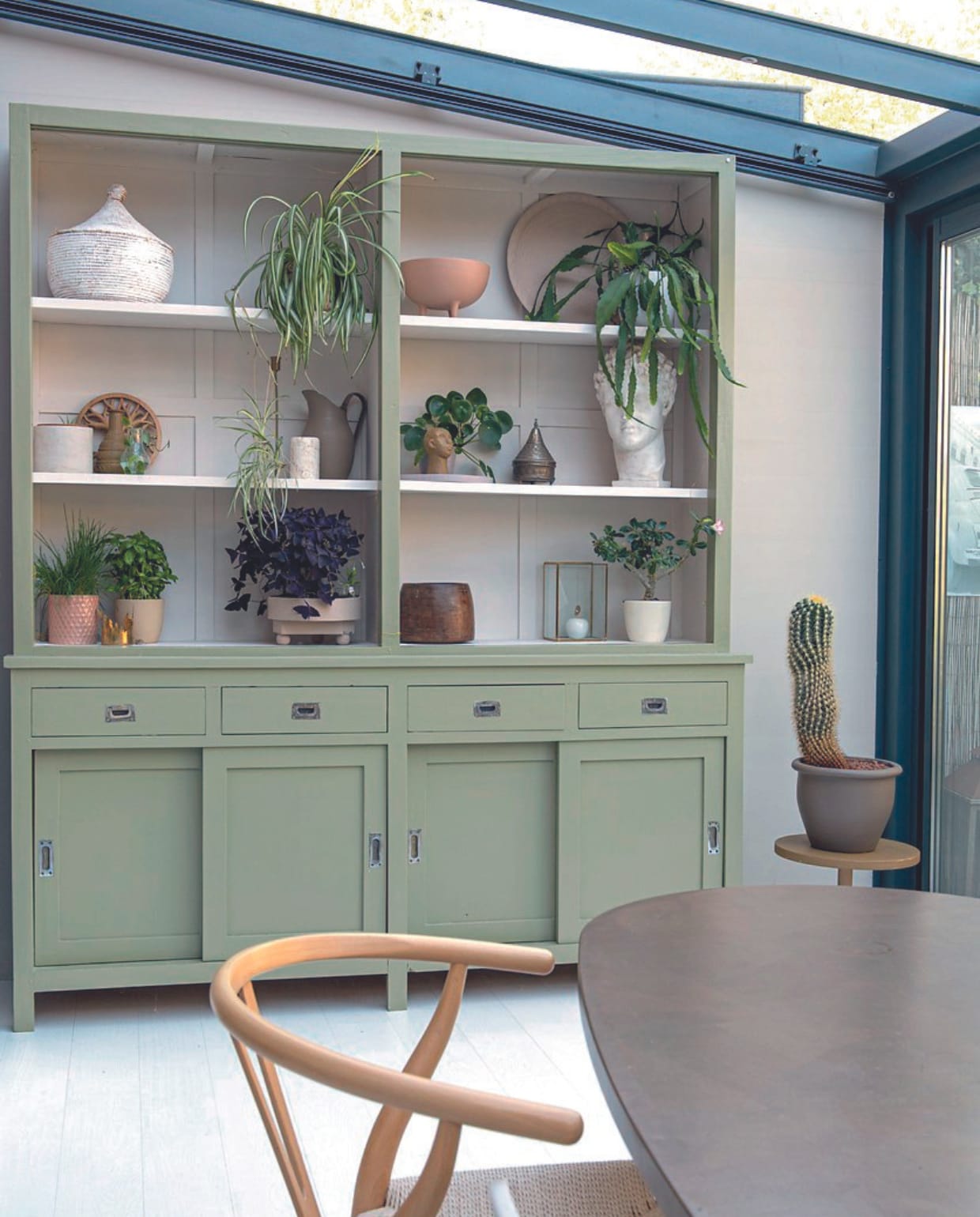 Kast van Marktplaats geschilderd in Moss van Lab Paint. In de kast vondsten van Marktplaats en souvenirs. Tafel Marktplaats, stoel Dominidesign, wandkleur Mushroom van Lab Paint. vtwonen 06-2024 | productie De Binnenkijkers | styling Jeske Weel | fotografie Caroline Coehorst