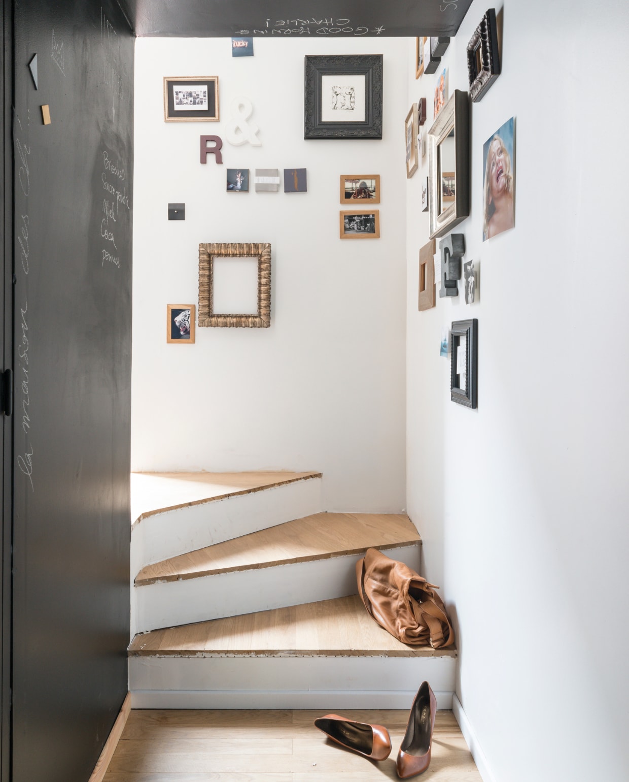 Het trapje leidt naar de entree, langs een wand vol familiefoto’s, tekeningen en sierobjecten. Houten dienblad van Habitat, keukenmachine van Kitchen Aid. vtwonen 03-2015 | Fotografie Julien Fernandez / amandinejules.com