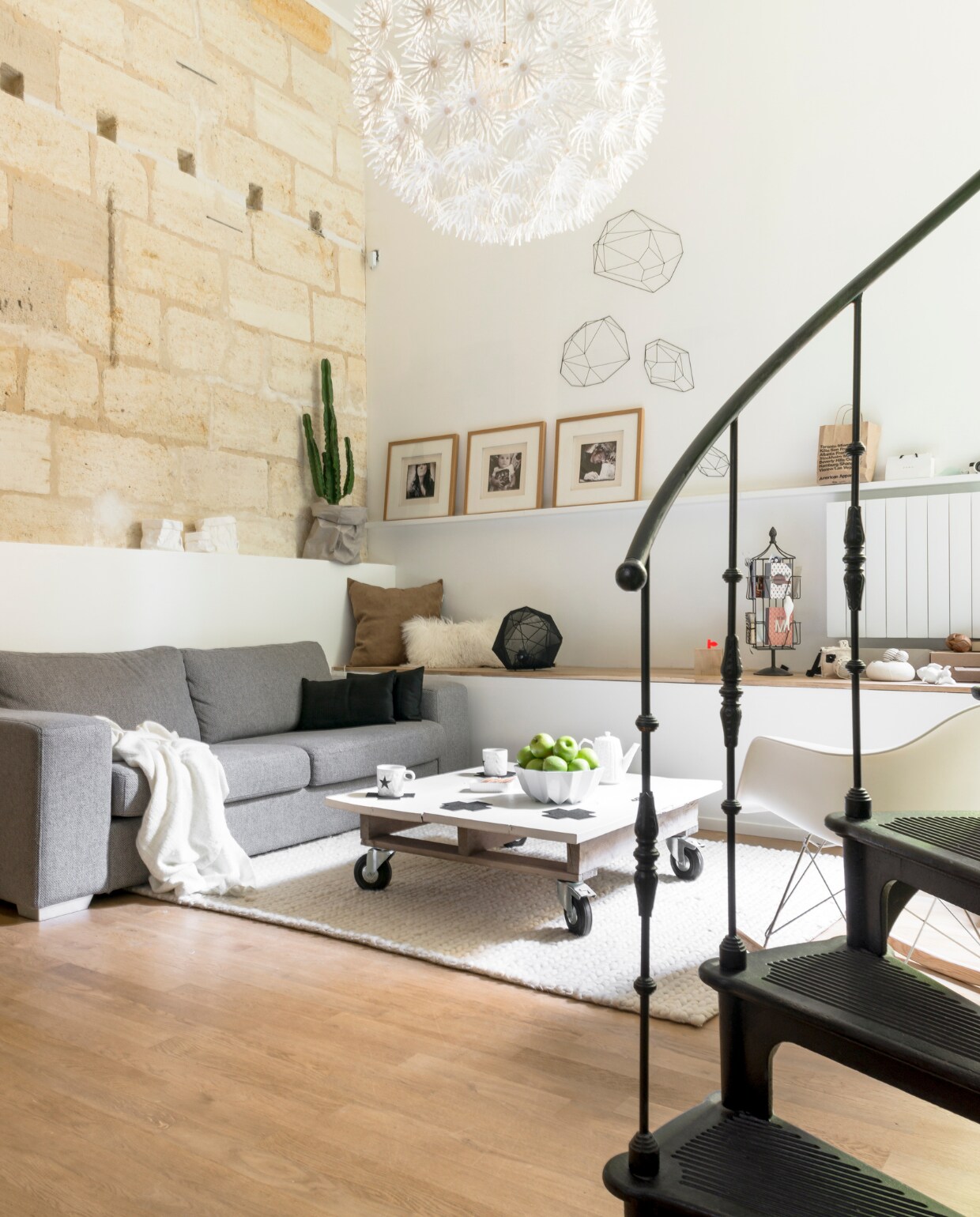 De bank is van de Franse woonketen Fly (www.fly.fr), het vloerkleed van AMPM, lamp van Ikea. De koffietafel is zelfgemaakt. De geometrische metalen objecten zijn van Habitat, de bekers van Bloomingville, de papieren plantenzak is van Uashmama. Schaal en theepot gekocht in Bordeaux, kaartenrekje cadeau. vtwonen 03-2015 | Fotografie Julien Fernandez / amandinejules.com