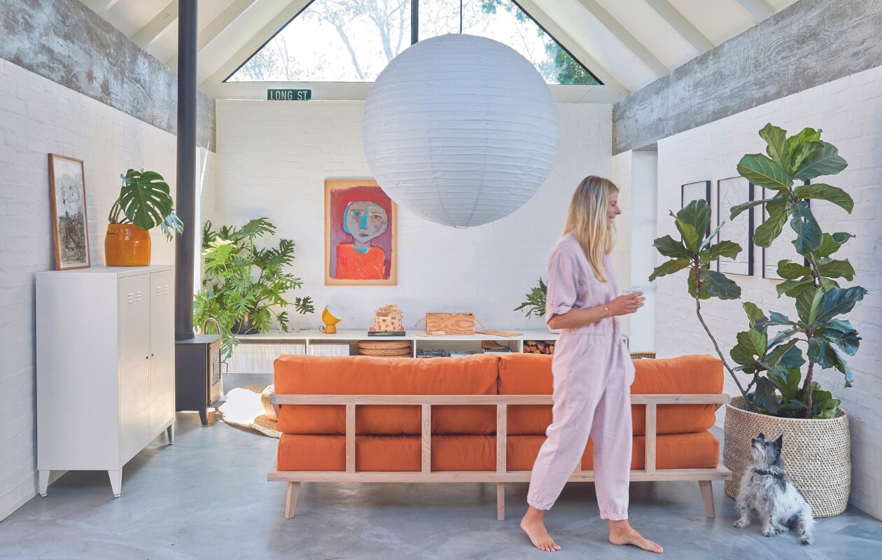 Maatwerk bank Kipekee Studio, stof in Tobacco van House of Fabrics (Kaapstad). Dressoir zelfgemaakt door Casey, ontwerp Beatty Vermeiren. Schilderij Jan Vermeiren, tafellamp Ikea PS collectie. Kachel Morsø, kast Mother City Hardware, gele plantenpot Pezula, muurverf Dulux. Vergelijkbaar: rijstpapieren hanglamp Hay, mand Urban Nature Culture. Planten onder andere Monstera en Ficus lyrata. vtwonen 07-2024 | productie Frank Features / Living Inside | fotografie Greg Cox