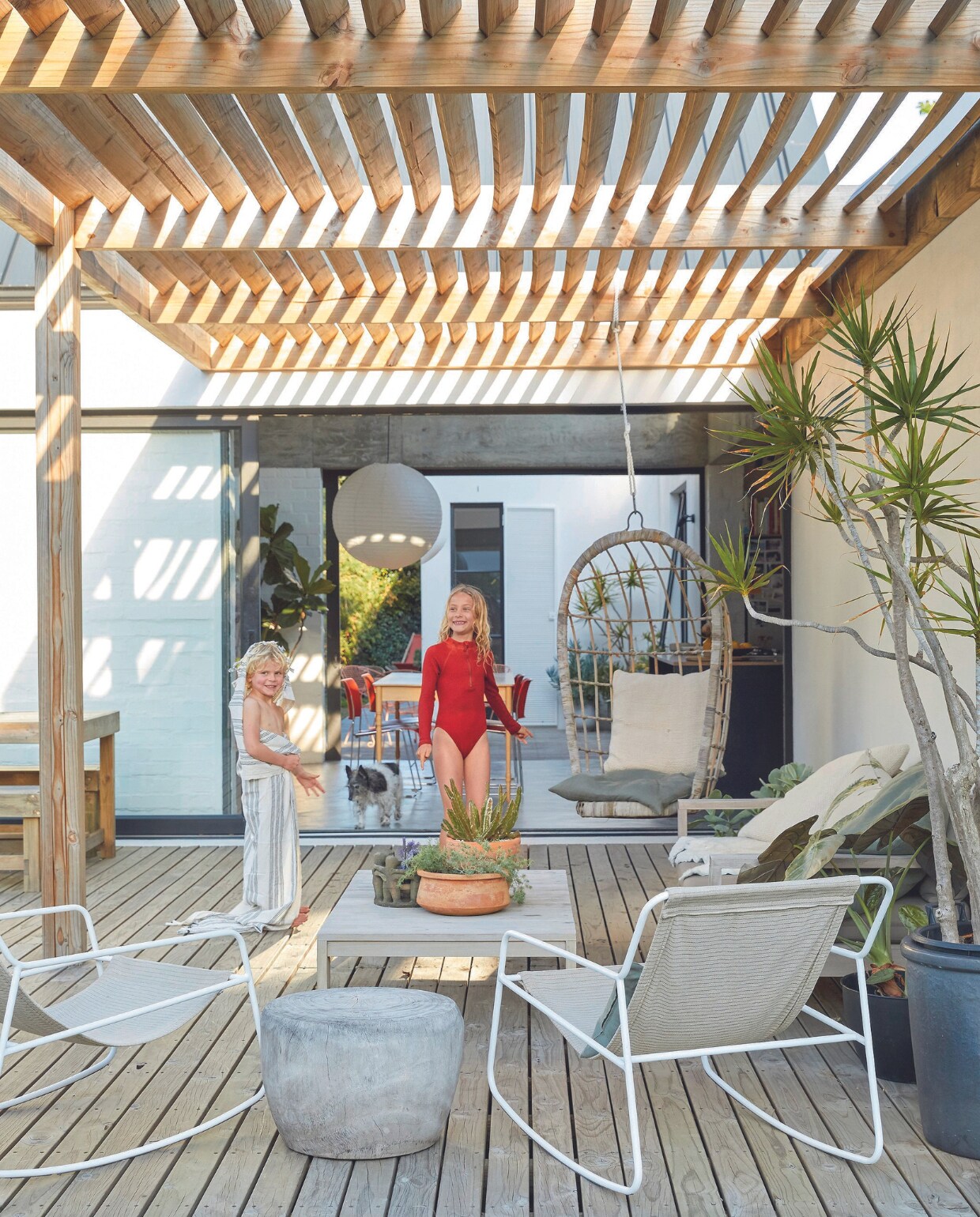 ergelijkbaar: rotan hangstoel Gamma, bijzettafel Pebble van vtwonen, witte tuinset Westwing. vtwonen 07-2024 | productie Frank Features / Living Inside | fotografie Greg Cox