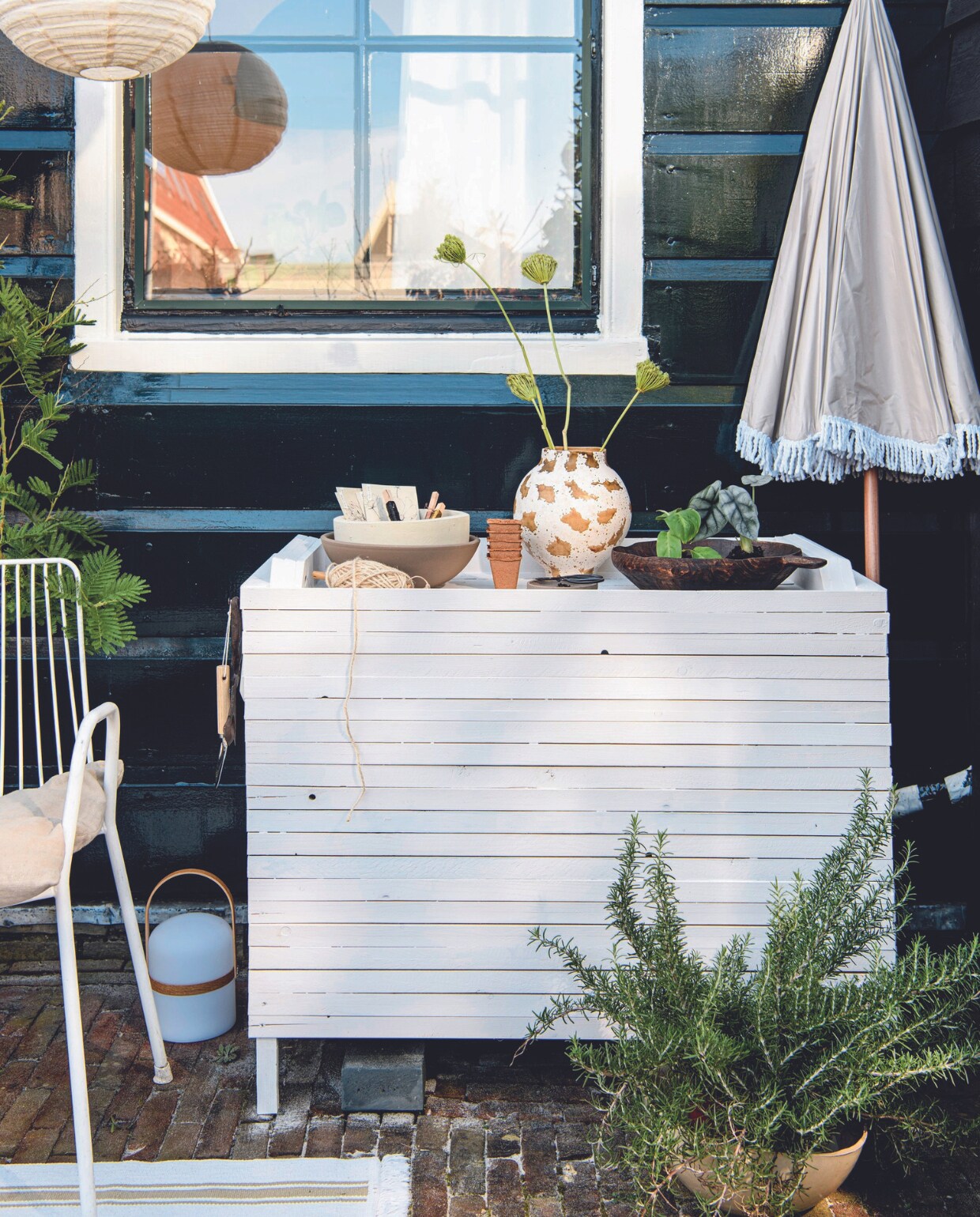 Mimosaboom € 59,95, rozemarijnplant € 24,95 (bloementuinaandezaan.nl). Metalen stoel Arty € 135,- (tikamoon.nl). Parasol Pescara van Human Nature, polyester en staal, 180 cm (Ø) € 44,99 (anwb.nl). Linnen kussenhoes € 14,99 (hm.com). Touw op houten klos € 4,80 (hobby-koopjes.nl). Keramieken vaas Heron € 62,95 en mangohouten schaal Modern rustic van Urban Nature Culture € 79,95 (zaanschfaamwebshop.nl). Terracotta schalen kringloop, geverfd met verfresten.Tafellamp € 49,99 (zarahome.com). Katoenen vloerkleed Sortsö, 55x85 cm € 3,99 (ikea.nl). Kweekpotjes, biologisch afbreekbaar, set van 5 € 1,95, schep € 2,95, vurenhouten steeketiketten, set van 10 € 2,50, tuinschaar € 4,95 (dille-kamille.nl). Smeedijzeren siernagel € 5,18 (deurbeslag.nl). Overig privébezit. vtwonen 07-2024 | styling Myla Griese | fotografie Louis Lemaire