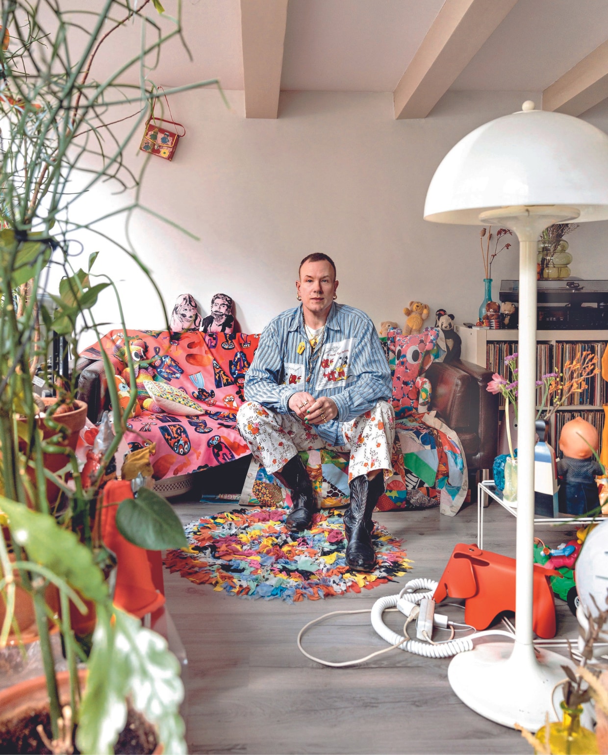 Kunstwerk stofzuiger gemaakt door Szabolcs Bozó, Bas’ bank ligt bomvol poppen en kussens. Hij past er zelf nog nét op. Bijzettafel Nesting van Max Sauze, wandlamp Raak, gele legerkist vintage. Ook vintage is de quilt die Bas op een vlooienmarkt in het Rose Bowl Stadion in Los Angeles vond. vtwonen 08-2024 | fotografie Ernie Enkelaar