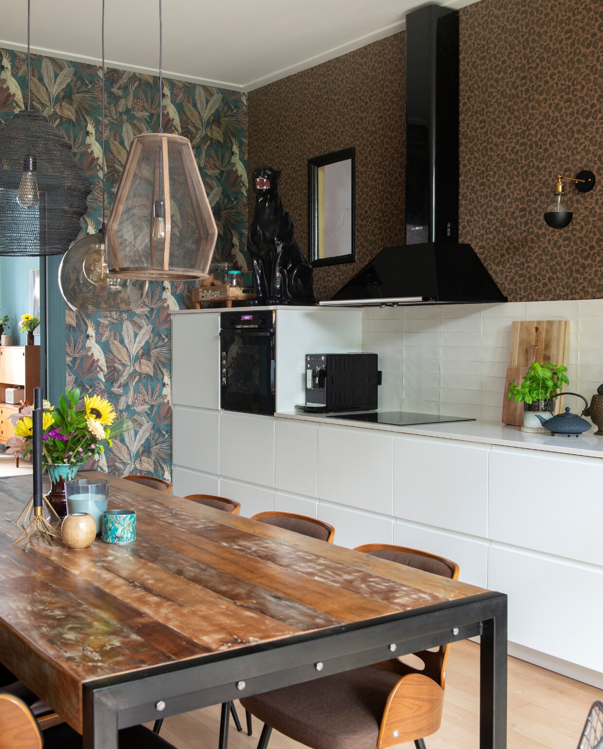 Keuken Ikea, composiet blad met marmerlook 123werkbladen. Tegels Friese Witjes, soortgelijke bij Harlinger Aardewerk &amp; Tegelfabriek. Behang Cheetah van BN Walls. Wandlampen Foir. Wandkast vintage vondst, uienpot en glaswerk kringloop, bloempot hoofd H&amp;M Home. Snijplank Ikea, object vogel Sissy-Boy, theepot Bredemeijer. Tafel Giga Meubel, stoelen Dutchbone. vtwonen 01-2021 | styling Jeske Weel | fotografie Caroline Coehorst