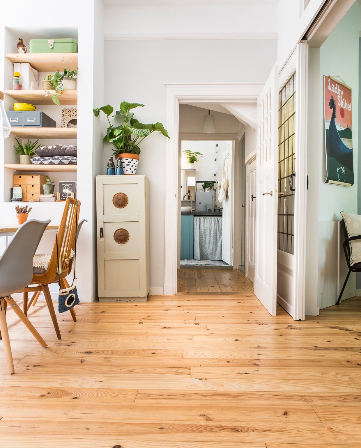 De grenenhouten vloer was een compromis, ik had liever iets lichters gehad, Jan is wat meer van warme houttinten. Achteraf vind ik het heel goed bij ons huis passen.’ De tafel is van Roeg Holt uit Groningen en op maat gemaakt, de kuipstoelen komen van wehkamp.nl, de middelste stoel is tweedehands en kocht Trudy in Drachten. Het gehaakte cameratasje komt bij Handmade Hopes vandaan, de lamp met kurken detail kocht Trudy bij Hornbach. De kast op de achtergrond was een keukenkast, Trudy vond ’m online. Oude poster van Beetje Heimwee, cactusvaas van Serax, de overige West Germany-vazen zijn vintage. vtwonen 02-2017 | fotografie Henny van Belkom