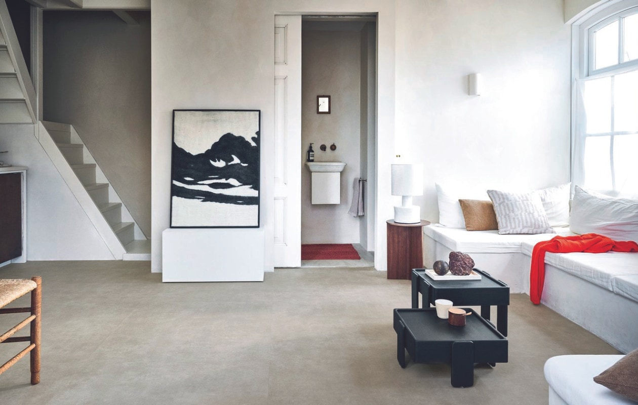 Pvc-vloer Basic XL in Sand, 91,4x91,4 cm, dryback per m² € 42,95.M.m.v. urbannatureculture.com (salontafels), vtwonen.nl/ shop (tafellamp van Serax, kussen met print, badmat van Sealskin, kunstwerk van Dutchbone, bijzettafel van Hay), skins.nl (handzeep van Aesop). vtwonen 08-2024 | styling Marlies Does | fotografie Sjoerd Eickmans