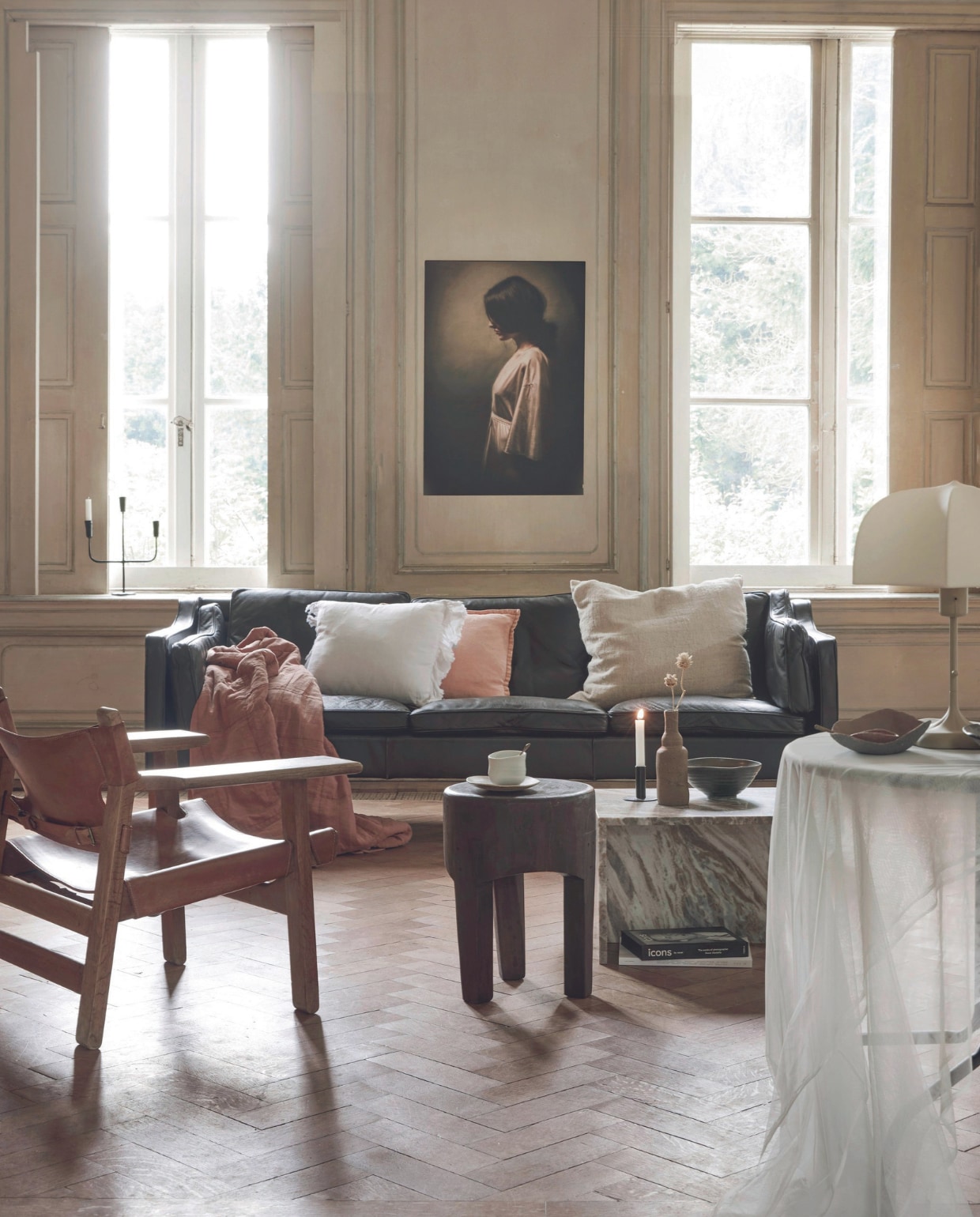Vintage leren bank van Børge Mogensen voor Fredericia, 220x78x82 cm (bxdxh) € 1950,-, vintage leren fauteuil The Spanish Chair van Børge Mogensen voor Fredericia € 2950,- (demachinekamer.nl). Houten kruk Poper van BePureHome, 35x45 cm (Øxh) € 159,-, marmeren salontafel Xhail van BePureHome, 50x50x35 cm (bxdxh) € 399,-, metalen kandelaar in vensterbank Sean van Woood € 34,95 (basiclabel.nl). Kunstwerk Reflections of Life van Marja van den Hurk, ArtFrame met zwart frame, 60x50 cm € 108,- (werkaandemuur.nl). Linnen kussen met ruche € 32,50, katoenen plaid Charlotte € 94,90, roze linnen kussen met piping € 32,50, zwarte kandelaar op tafel € 11,50 (mrsbloom.nl). Crèmekleurig kussen Nettle van Ferm Living, katoen en brandnetel € 89,99, tafellamp Poem van Ferm Living, staal en stof € 269,- (vtwonen.nl/shop). Keramieken schotel Wabi Sabi eggshell, uit set € 179,- porseleinen kop Matcha tea bowl, set van 2 € 70,-, keramieken vaas € 98,-, keramieken kom ernaast Wabi Sabi L, set van 2 € 115,- (marjokedeheer.com). Kom met schulprand € 15,- (lckeramiek.nl). Tule over tafel, per meter € 3,65 (aboeken.nl). vtwonen 09-2024 | styling Marlies Does | fotografie Peggy Janssen